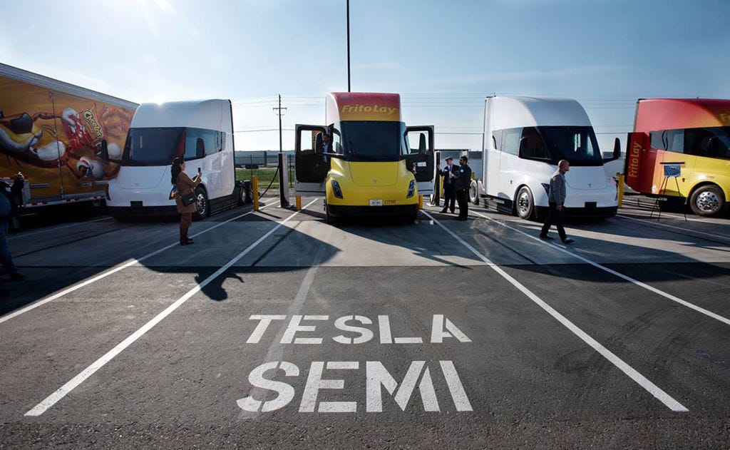 Mehrere Tesla Semi-Trucks auf einer Strecke, auf deren Straße „Tesla Semi“ aufgemalt ist