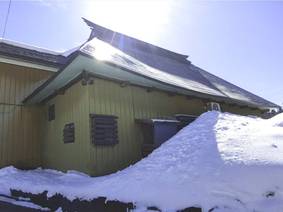 Eine Akiya, bei der eine Seite des Gebäudes durch einen riesigen Schneehaufen blockiert ist.