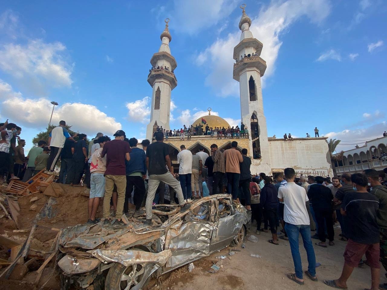 Demonstranten stehen im Rahmen einer Protestaktion vor der Al-Sahaba-Moschee auf einem beschädigten Gelände.