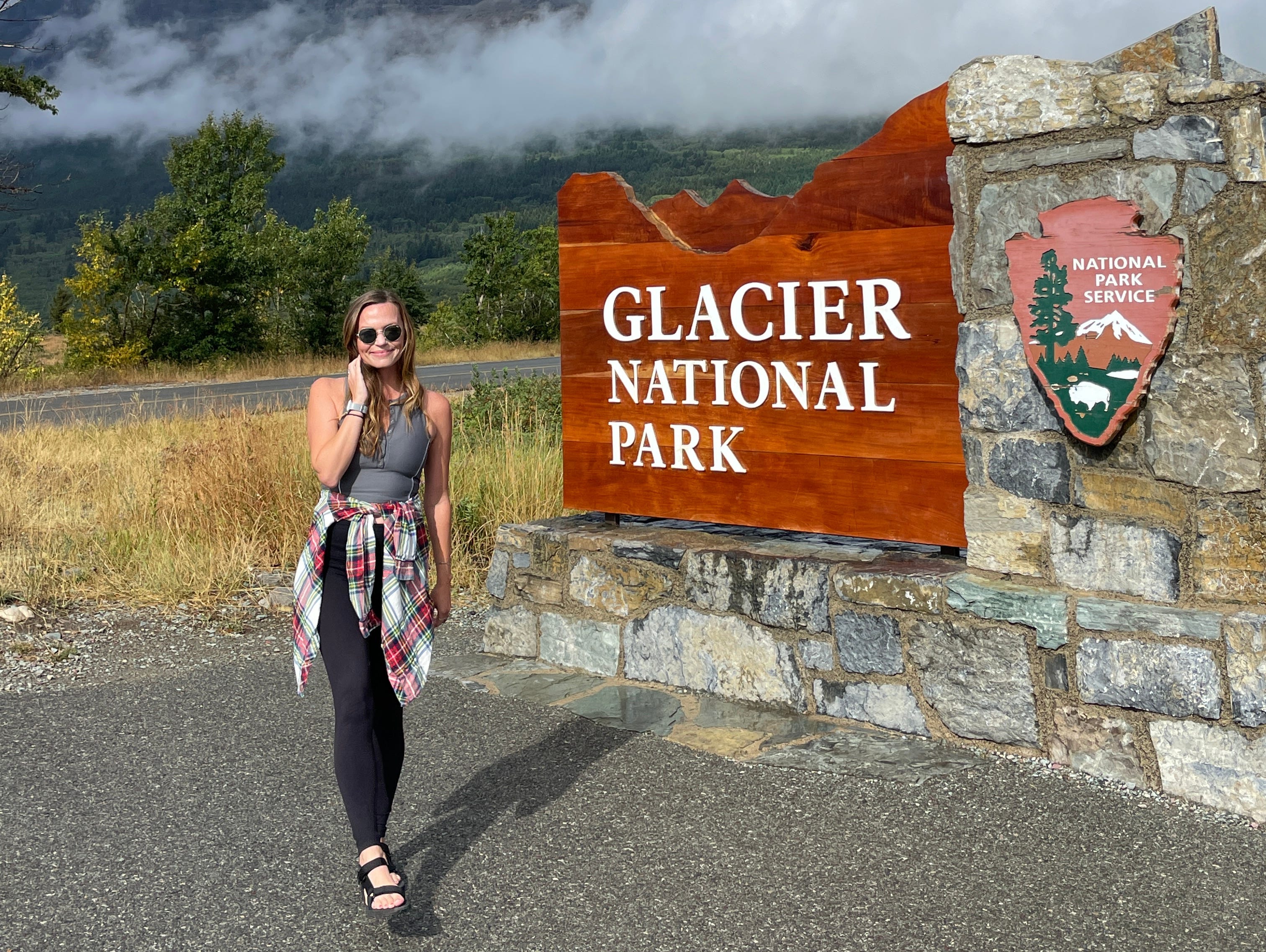 Eine Frau steht vor dem Glacier-Nationalpark-Schild.