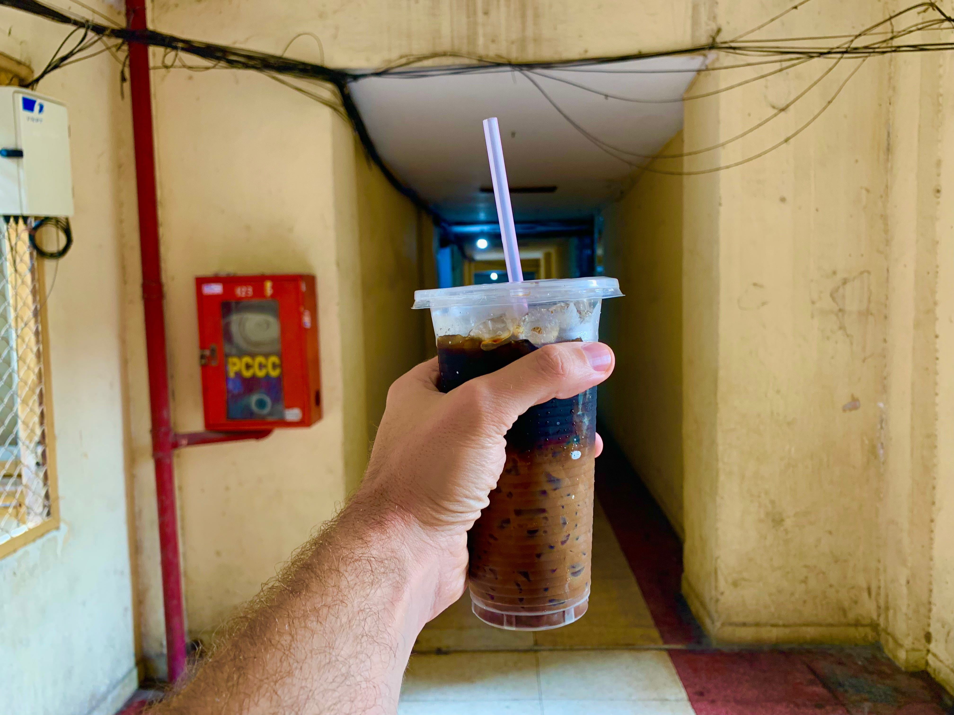 Hand hält eine Tasse vietnamesischen Eiskaffee hoch
