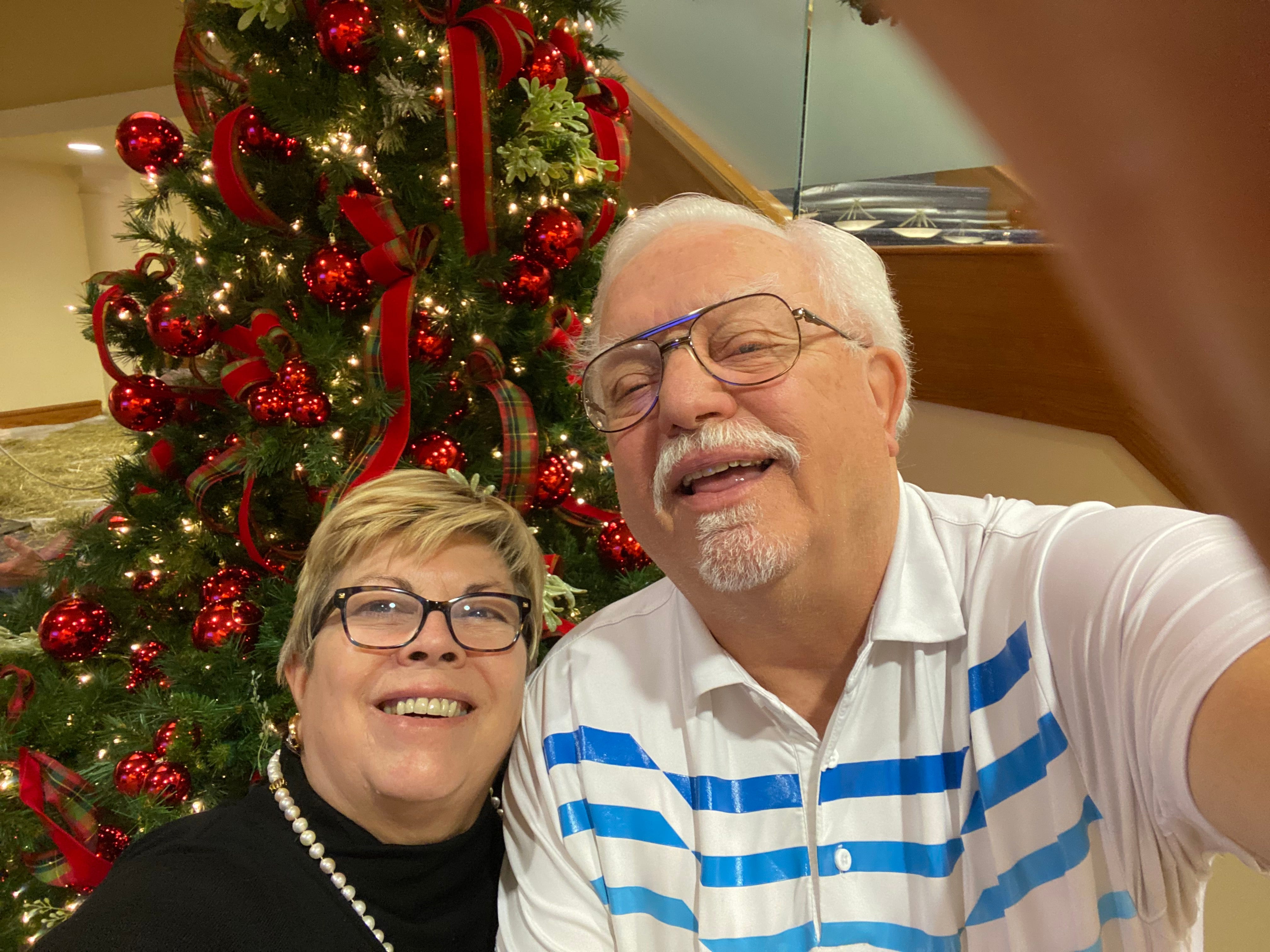 Die frisch verheirateten Senioren Judy und Evans Wagner machen an Bord einer Kreuzfahrt ein Selfie vor einem Weihnachtsbaum.