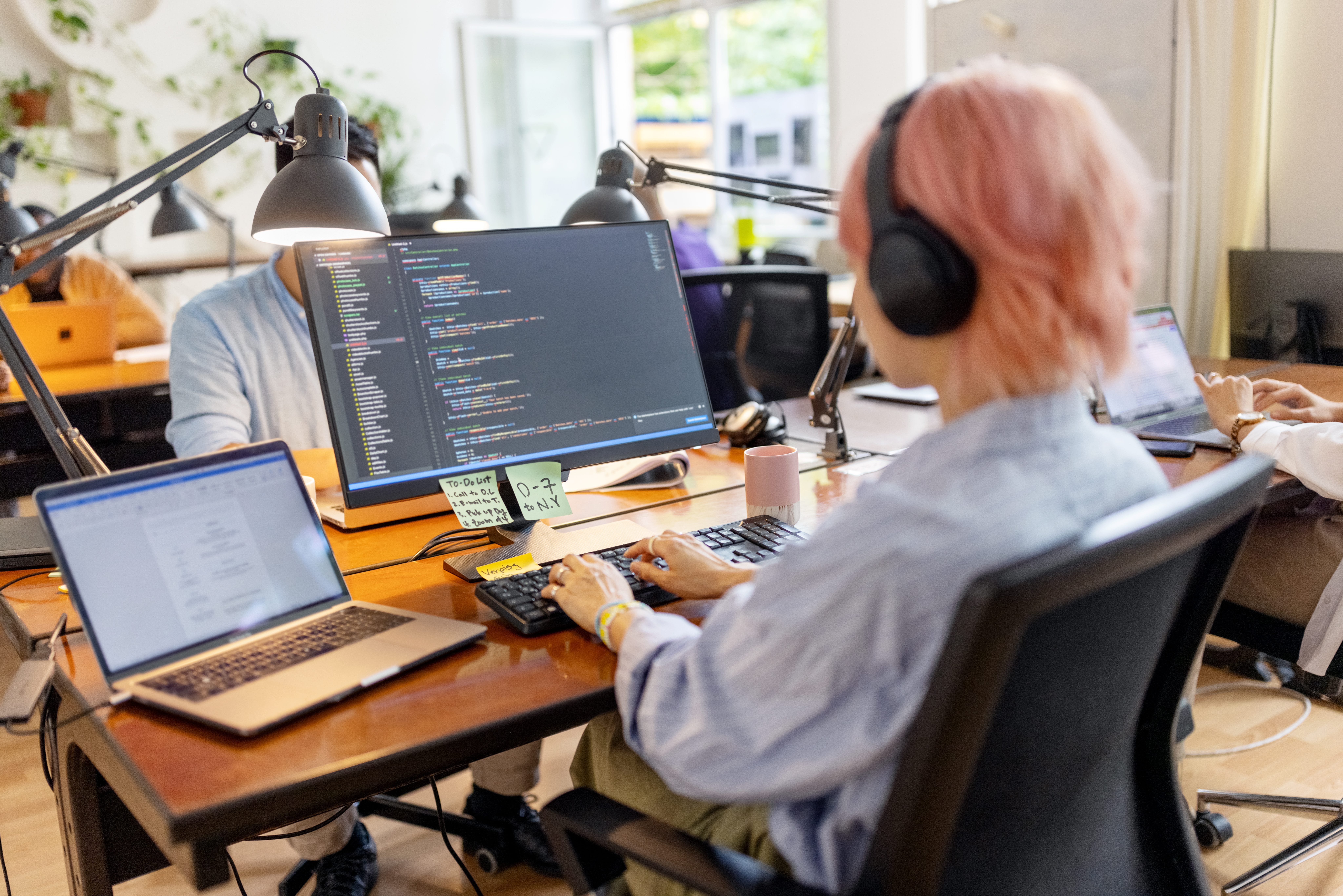 Ein Softwareentwickler trägt Kopfhörer, während er an einem Schreibtisch sitzt und am Computer programmiert.