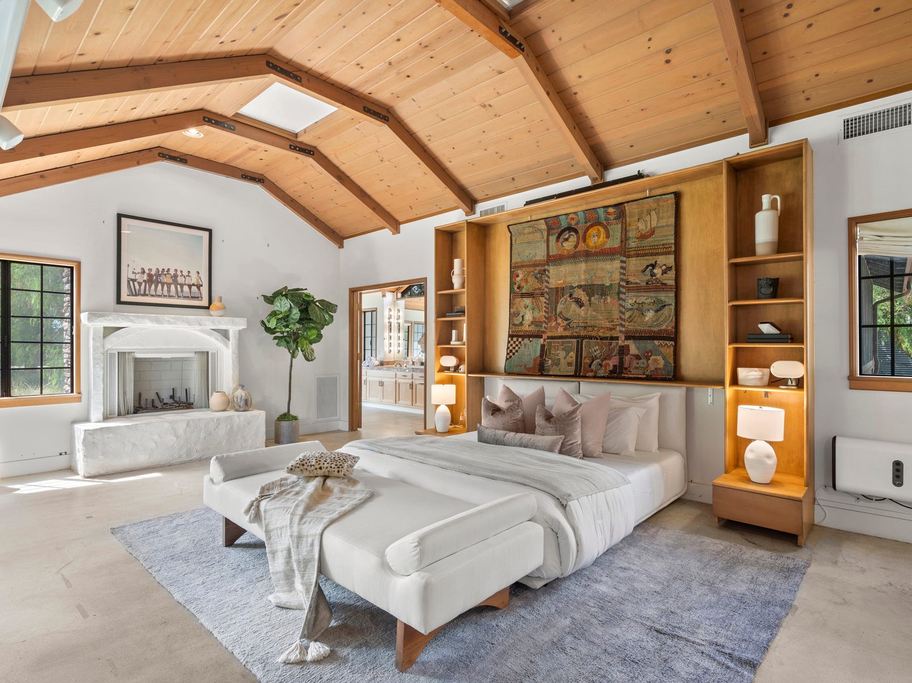Ein großes Schlafzimmer mit weißen Wänden, freiliegenden Holzbalken und -decken und einem weißen Bett