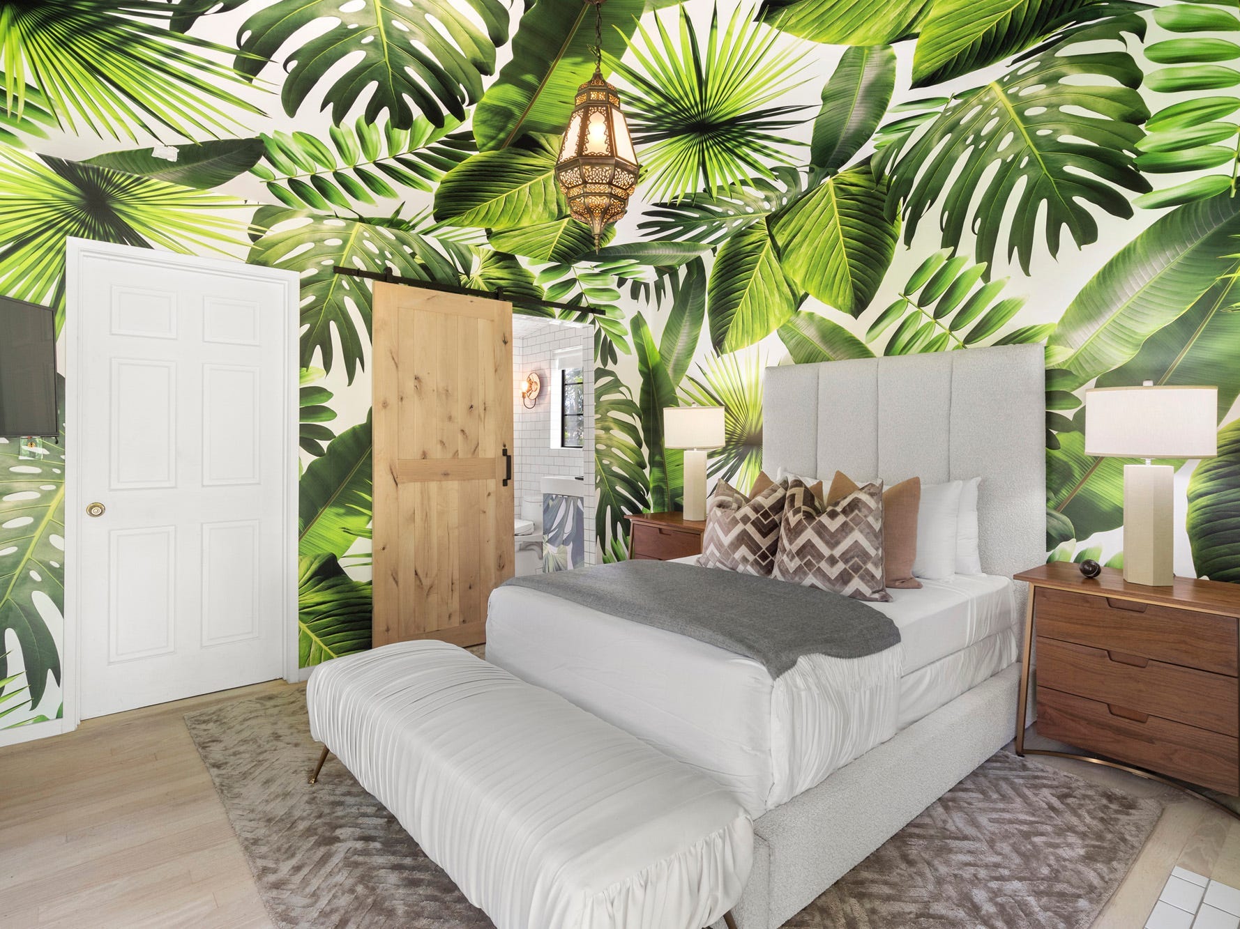 Ein mit Palmwedeln bemaltes Zimmer und ein kleines weißes Bett