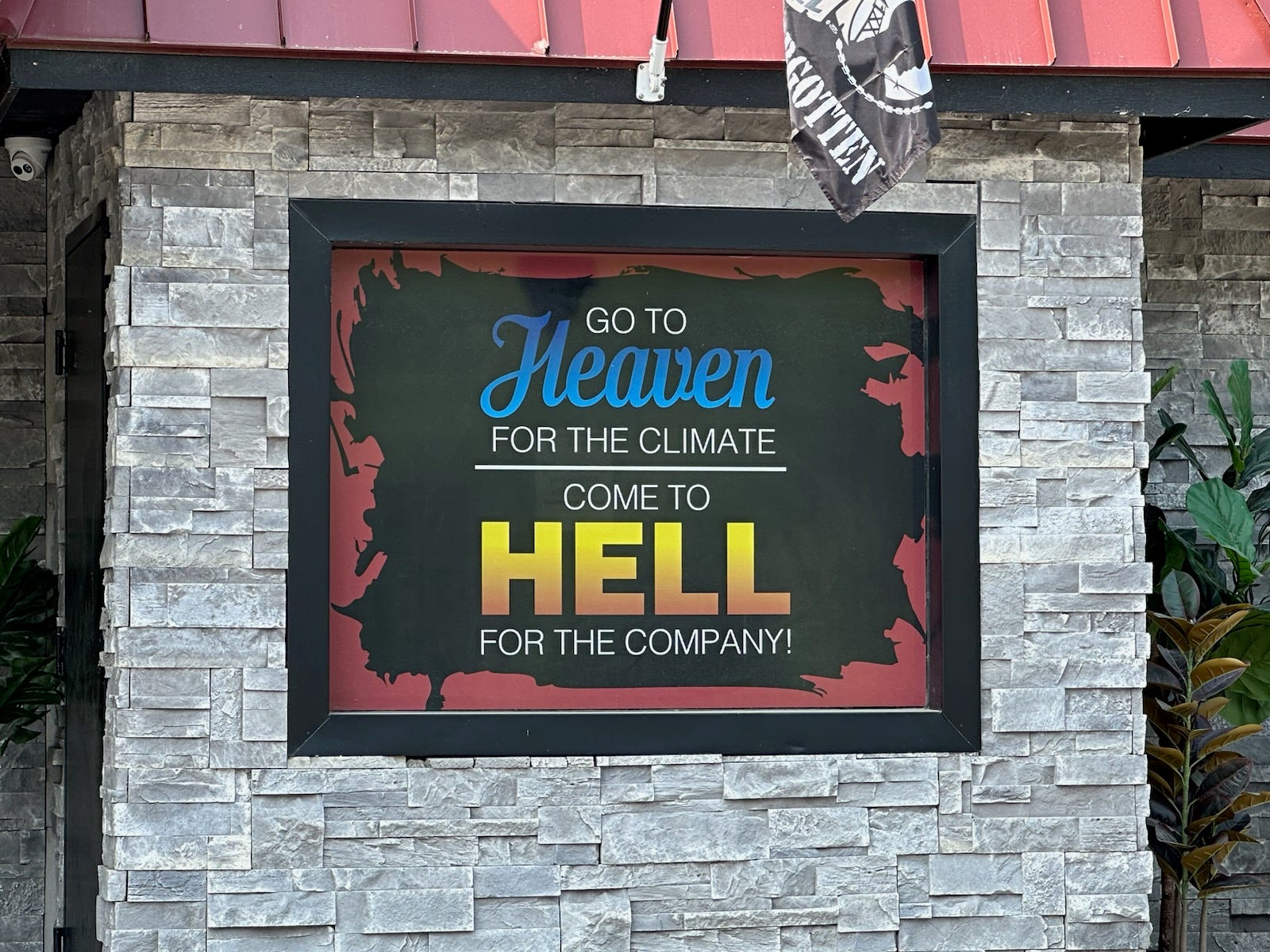 Schild am Gebäude mit der Aufschrift „Für das Klima in den Himmel kommen, für das Unternehmen in die Hölle kommen“