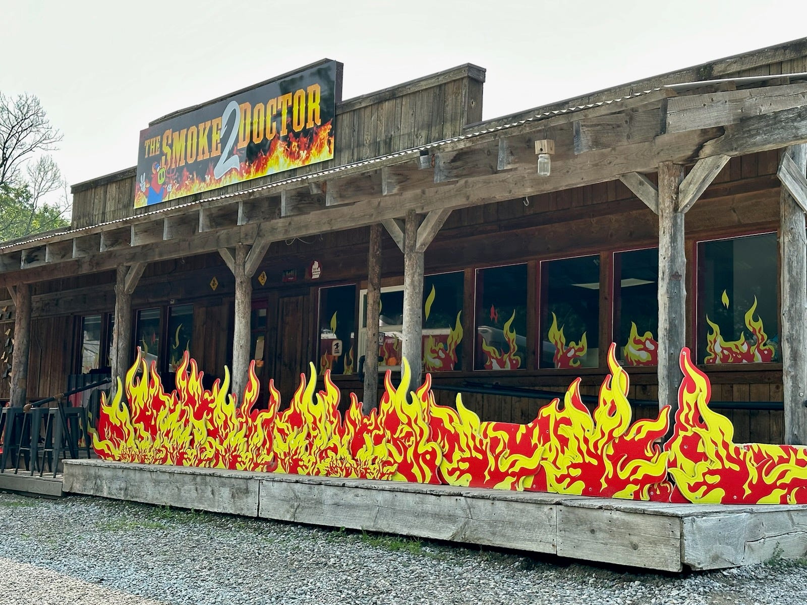 Das Restaurant Smoke 2 Doctor, ein Holzgebäude, das mit künstlichen roten und gelben Flammen bedeckt ist 