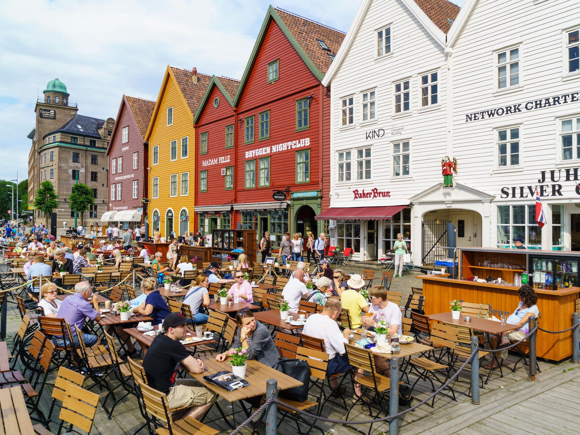 Open-Air-Restaurants und Cafés vor den hölzernen Hanse-Kaufmannsgebäuden von Bryggen, einem alten Fjordkai, heute eine wichtige Touristenattraktion und UNESCO-Weltkulturerbe, Bergen, Norwegen.