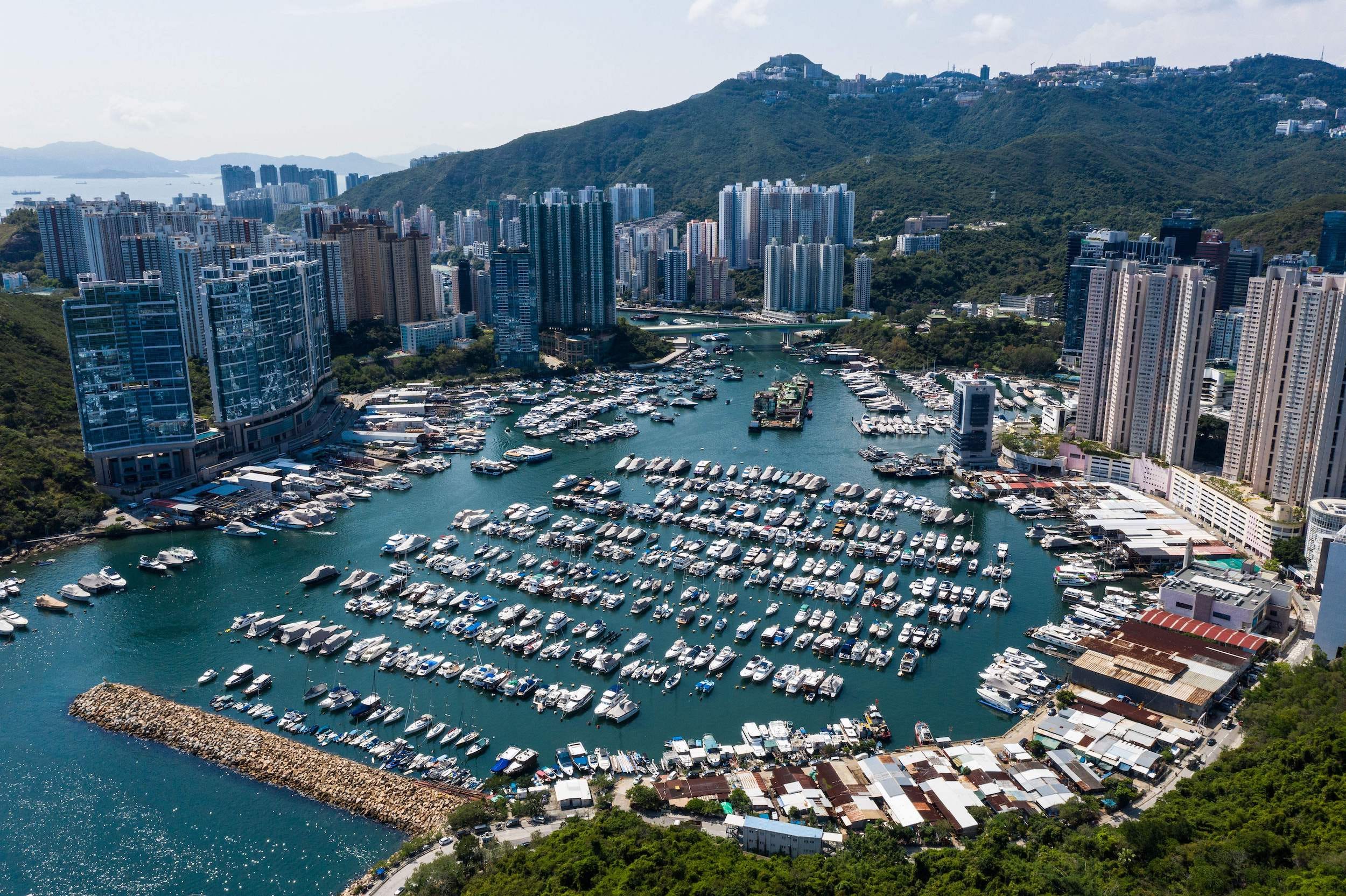 Eine Luftaufnahme des Hafens von Aberdeen mit Reihen moderner Boote, umgeben von Wohn- und Geschäftsgebäuden in Hongkong.