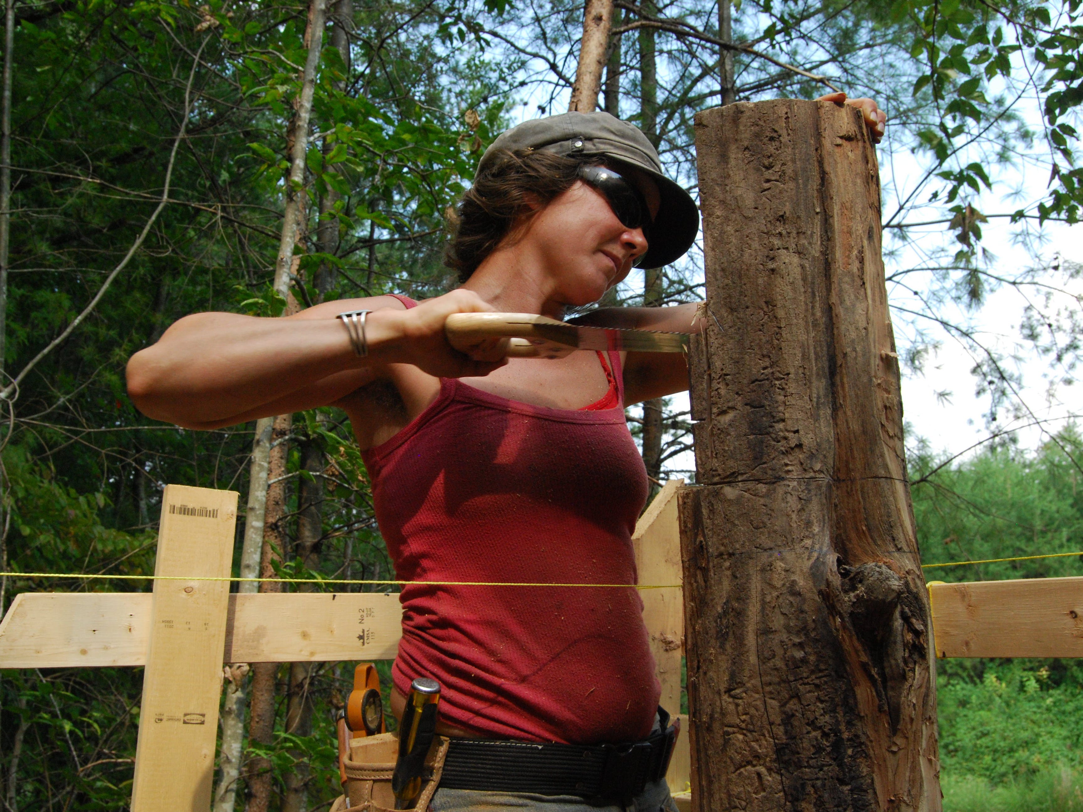 Eine Frau arbeitet an den Baumstämmen ihrer Hütte.