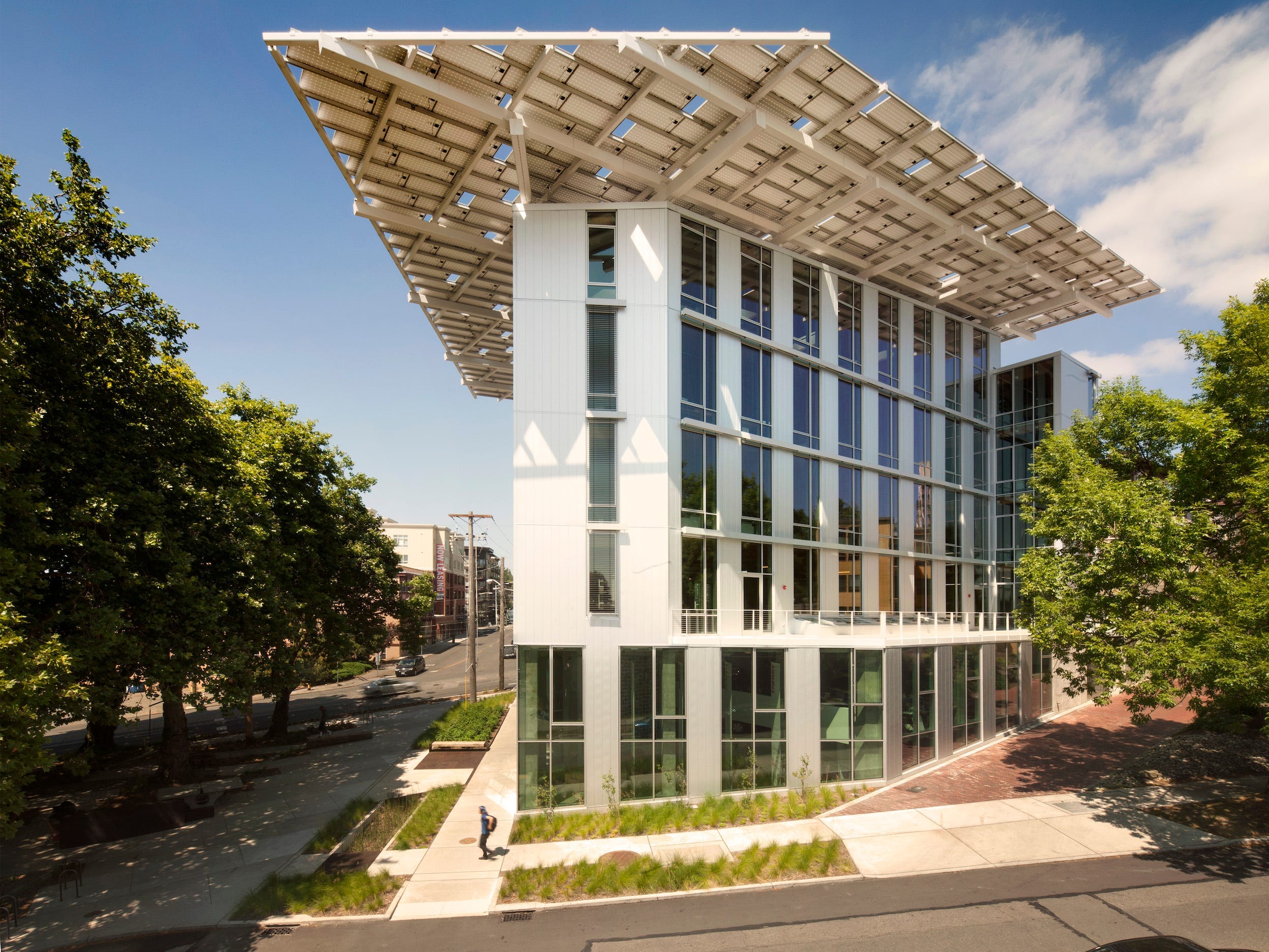 Ein Foto von der Außenseite des Bullitt Center in Seattle, Washington.  Das Gebäude ist hoch und dünn, hat viele Fenster und ein großes Vordach.