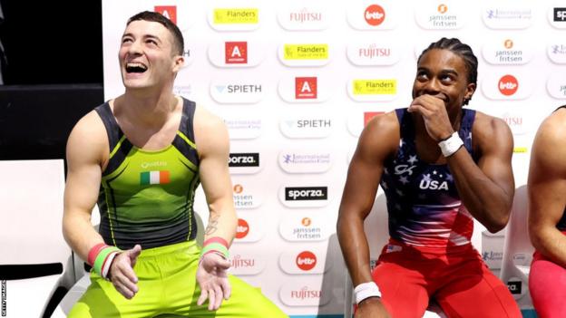 Rhys McClenaghan reagiert, nachdem er realisiert hat, dass er in Antwerpen die Goldmedaille gewonnen hat, während Silbermedaillengewinner Khoi Young zusieht