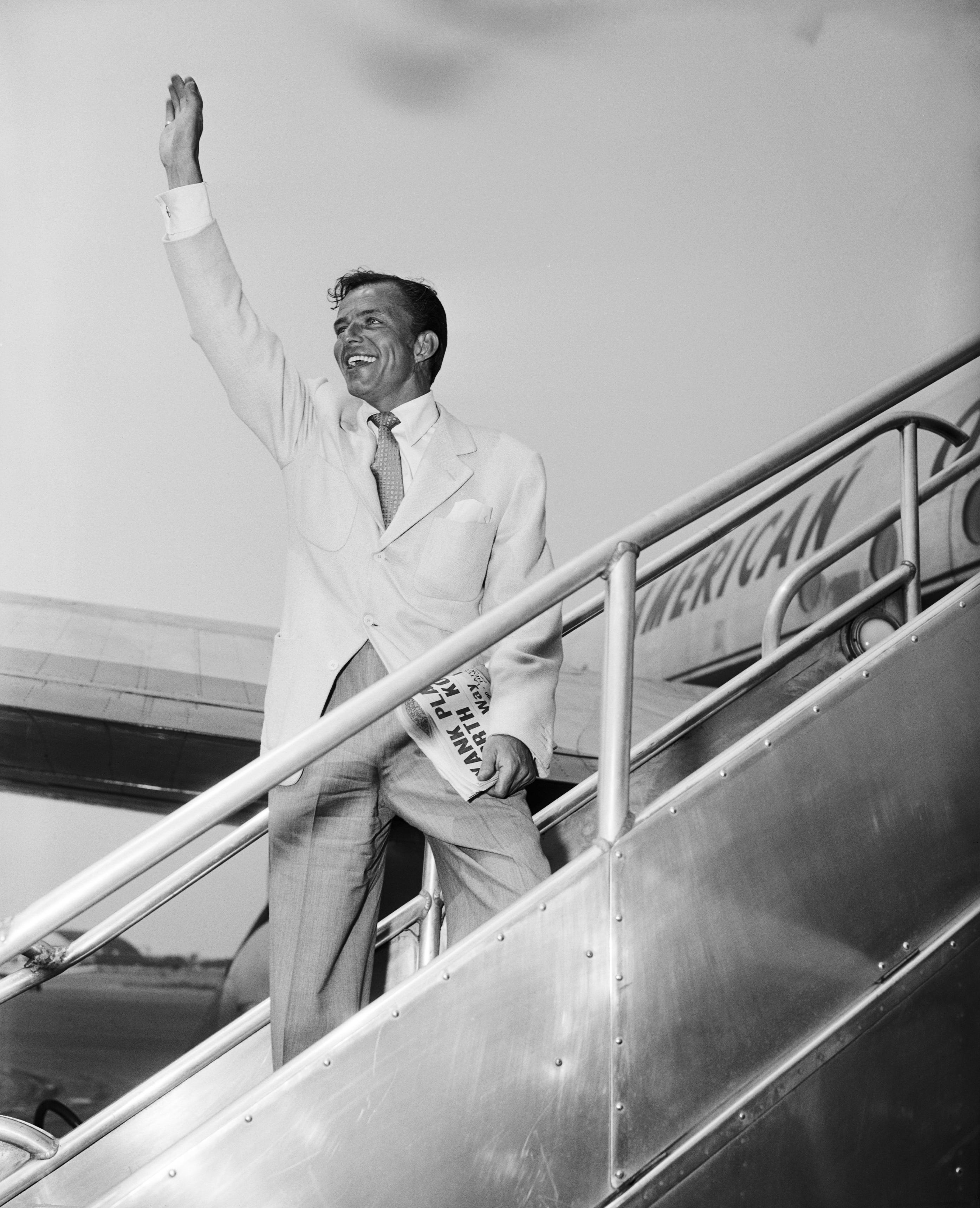 Frank Sinatra winkt am Flughafen Idlewild zum Abschied, kurz bevor er mit American Overseas Airlines nach London abfliegt;  30.06.1950, Queens, New York
