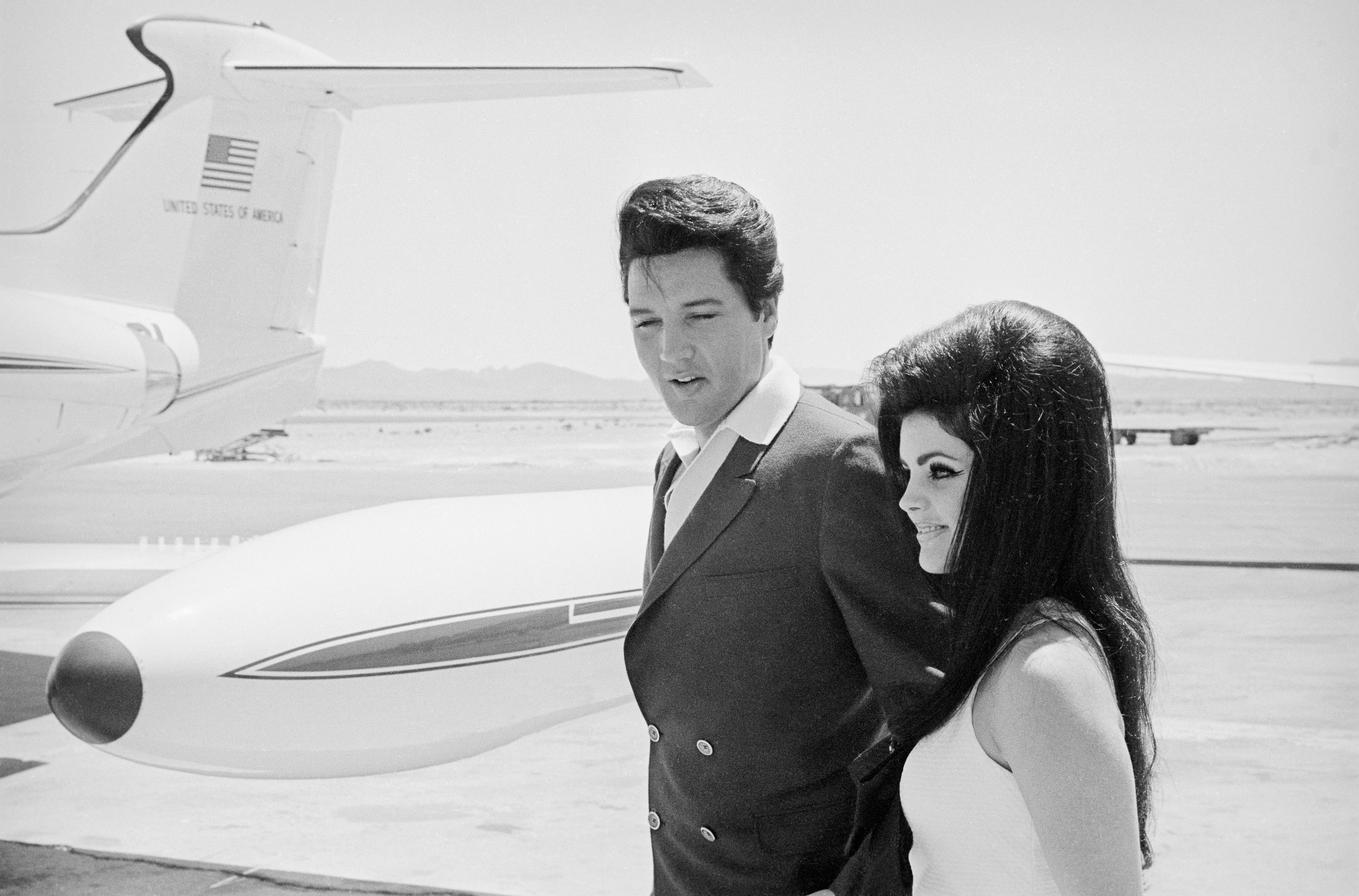 Sänger Elvis Presley und seine Braut Priscilla Ann Beaulieu lächeln glücklich, als sie sich darauf vorbereiten, nach ihrer Hochzeit im Aladdin Hotel ein gechartertes Düsenflugzeug zu besteigen;  1. Januar 1967.