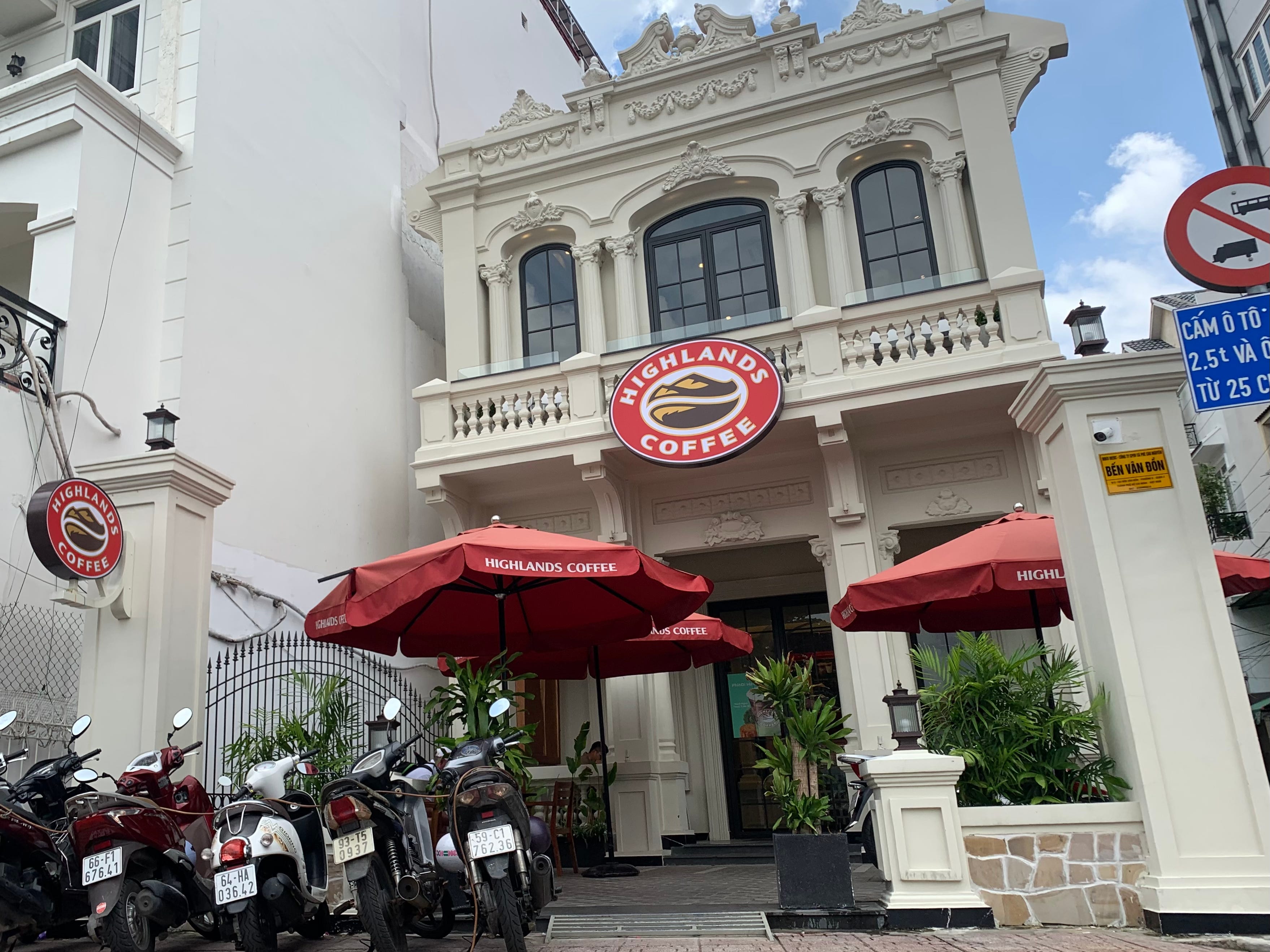 Gebäude in Ho-Chi-Minh-Stadt, in dem sich ein Café befindet, vor dem Motorräder geparkt sind.