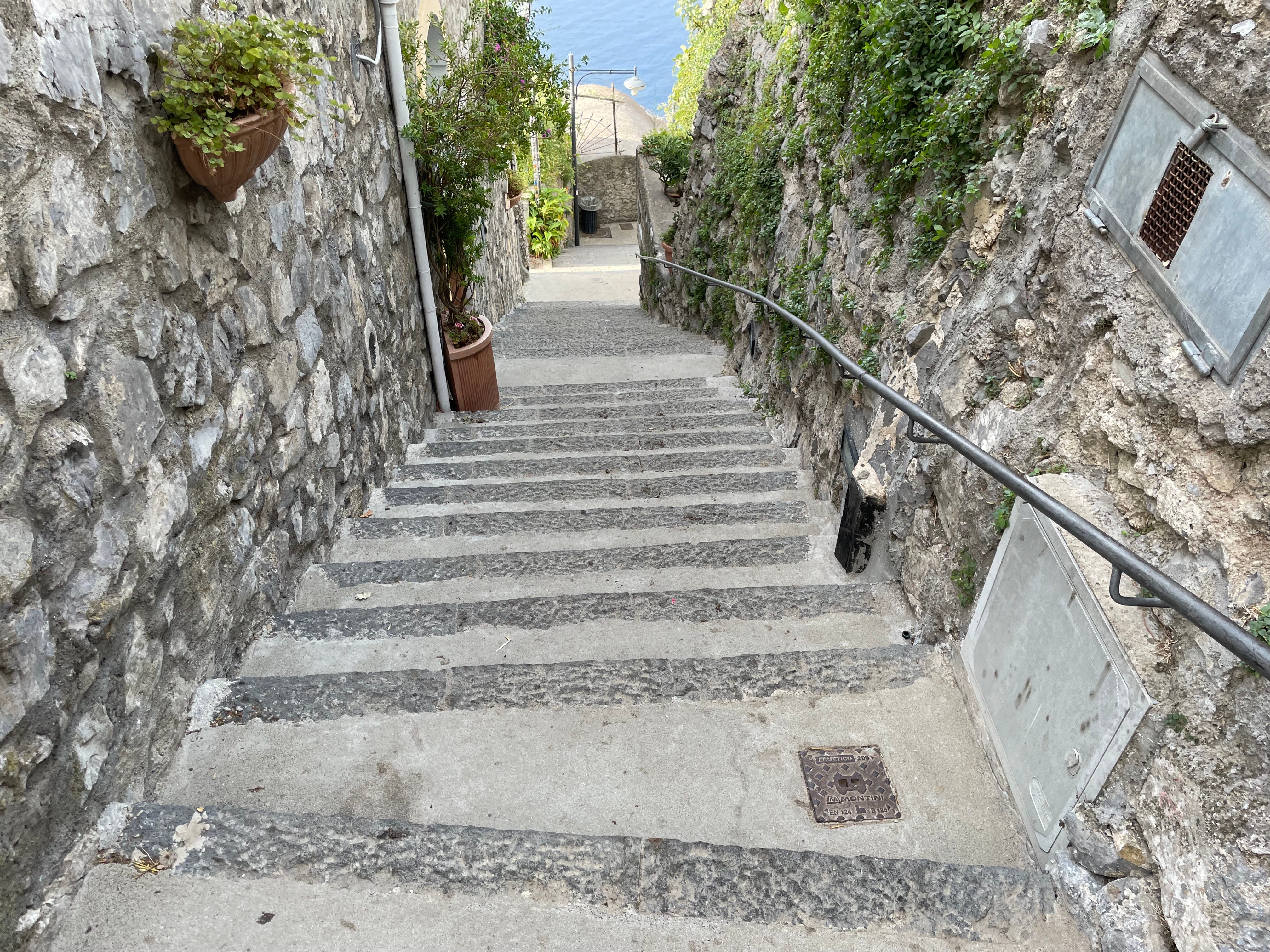 Viele Stufen mit einem Geländer auf der rechten Seite und Steinmauern auf jeder Seite.