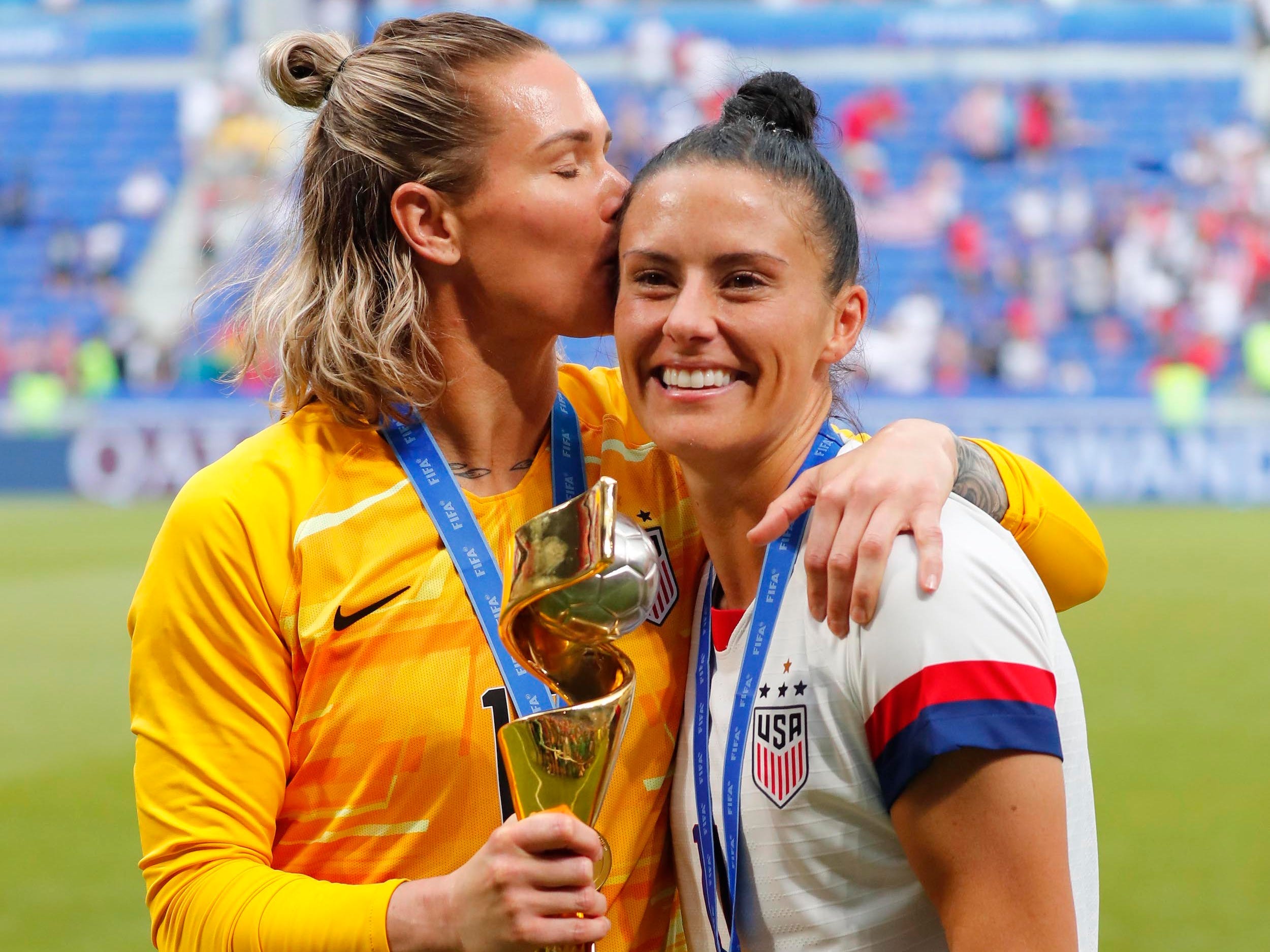 Ashlyn Harris (links) küsst Ali Krieger, während sie mit der WM-Trophäe 2019 posieren.