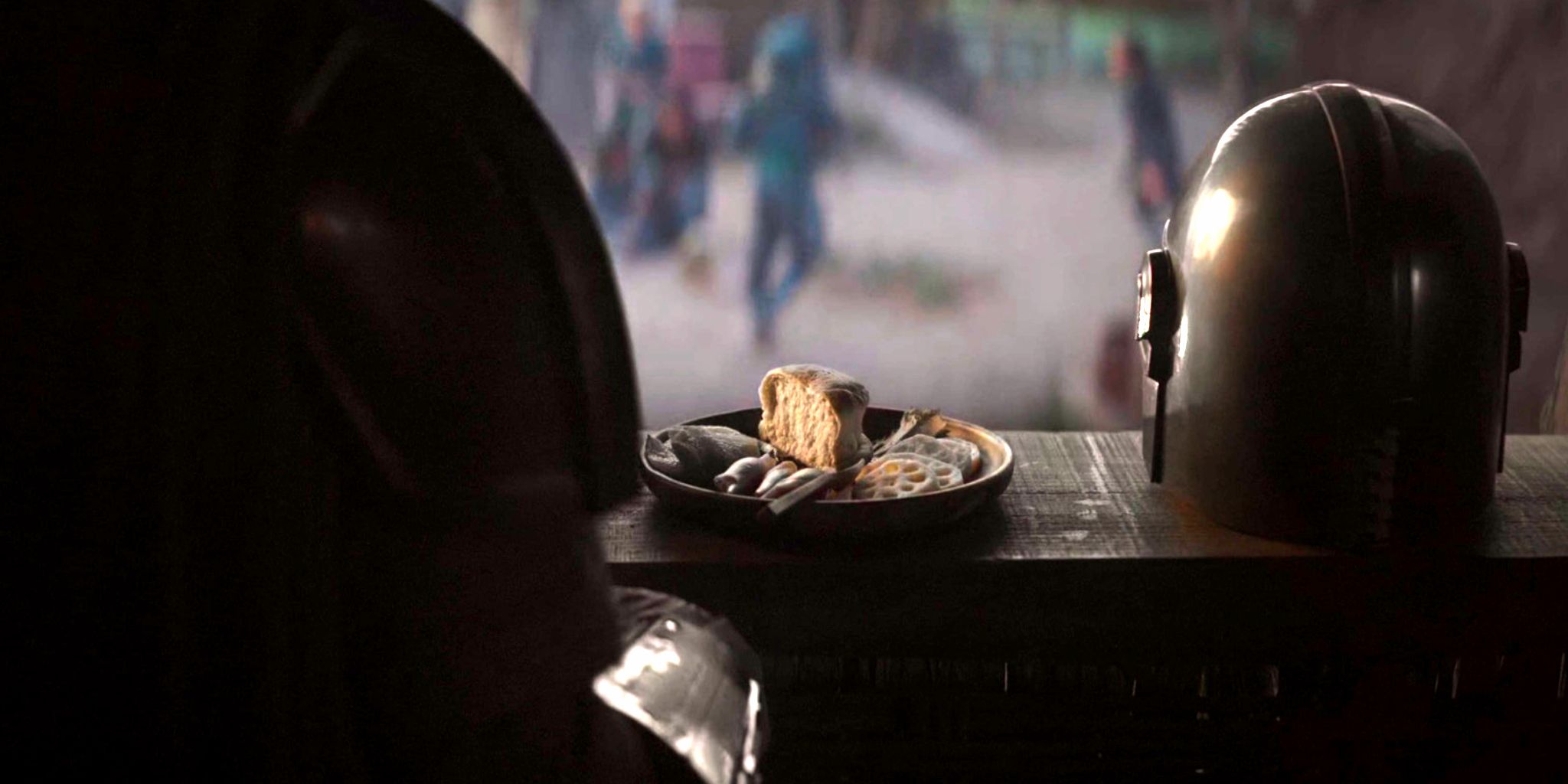Din Djarin sitzt neben seinem abgenommenen Helm zum Essen in Episode 4 von The Mandalorian