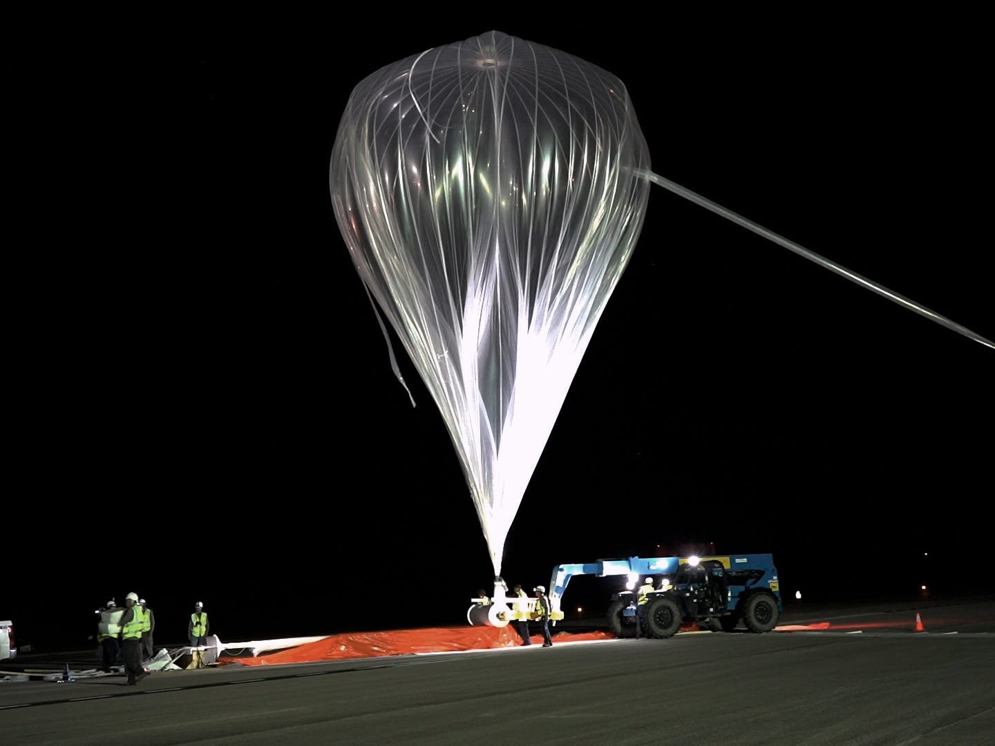 Eine Besatzung hisst nachts einen großen, durchsichtigen Ballon