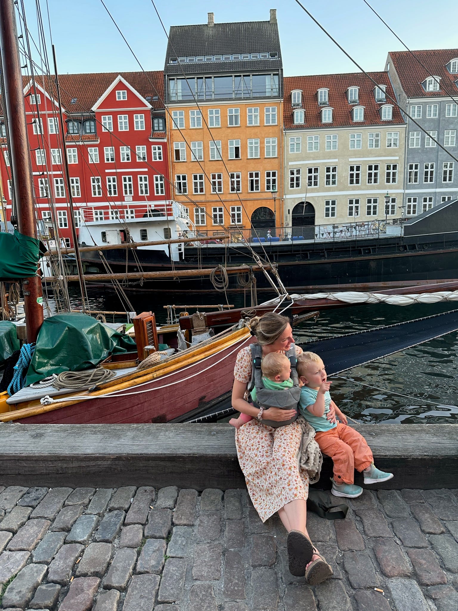 Eine Frau sitzt mit zwei Kindern vor einem Kanal in Dänemark.