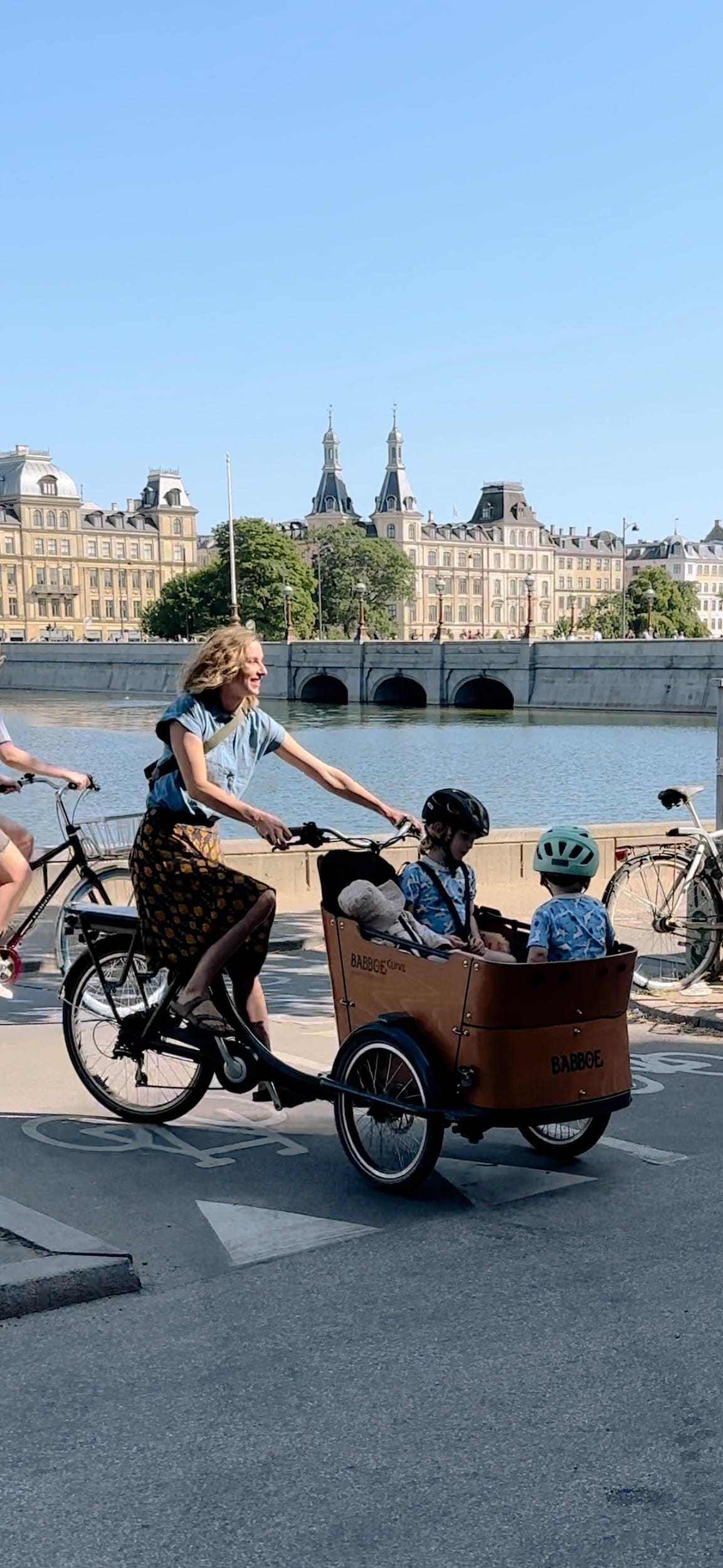 Eine Frau fährt Fahrrad mit ihren Kindern vorne.