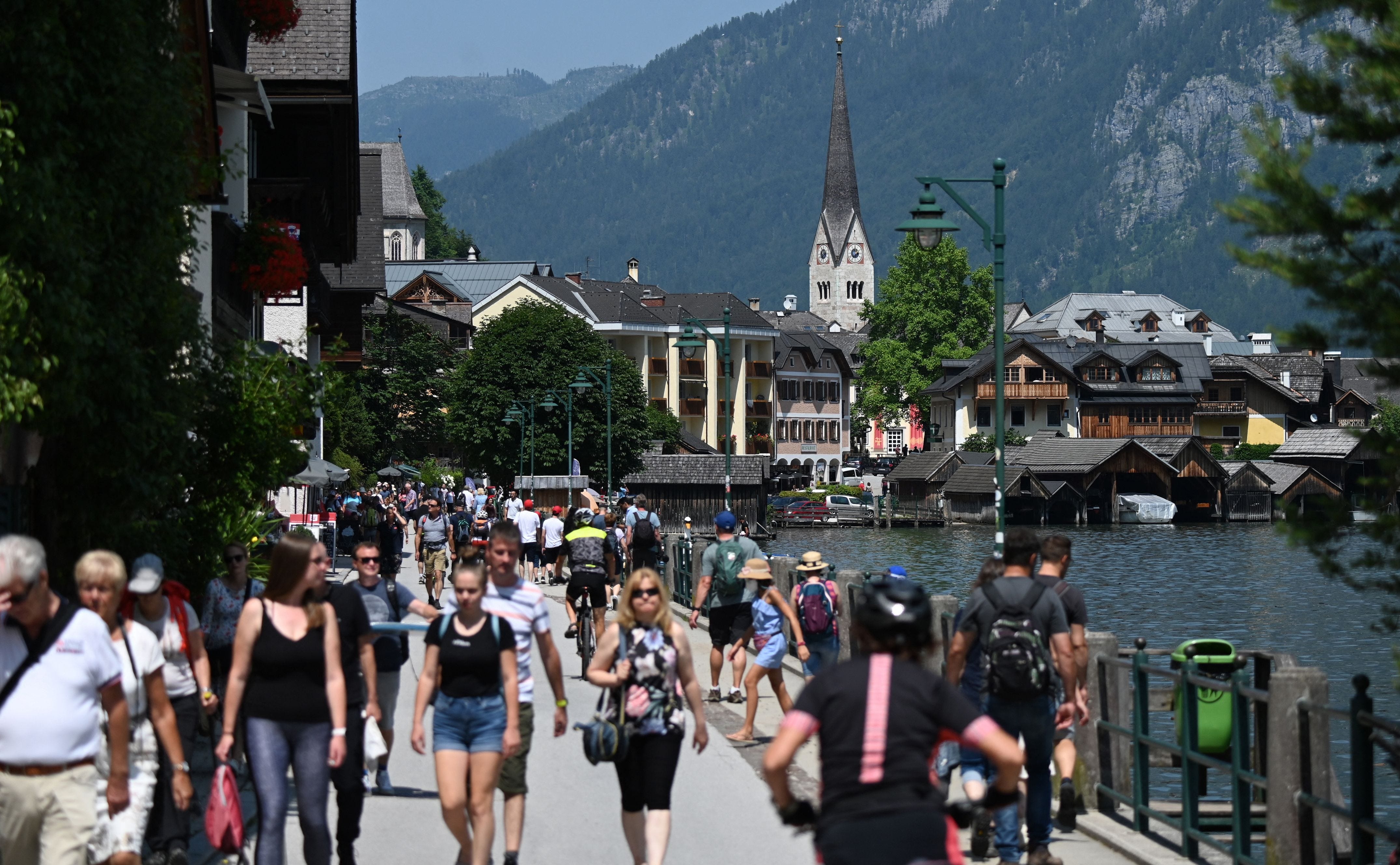 Touristen besuchen am 21. Juli 2021 die Stadt Hallstatt am Hallstättersee mit der Evangelischen Kirche im Zentrum, Oberösterreich.