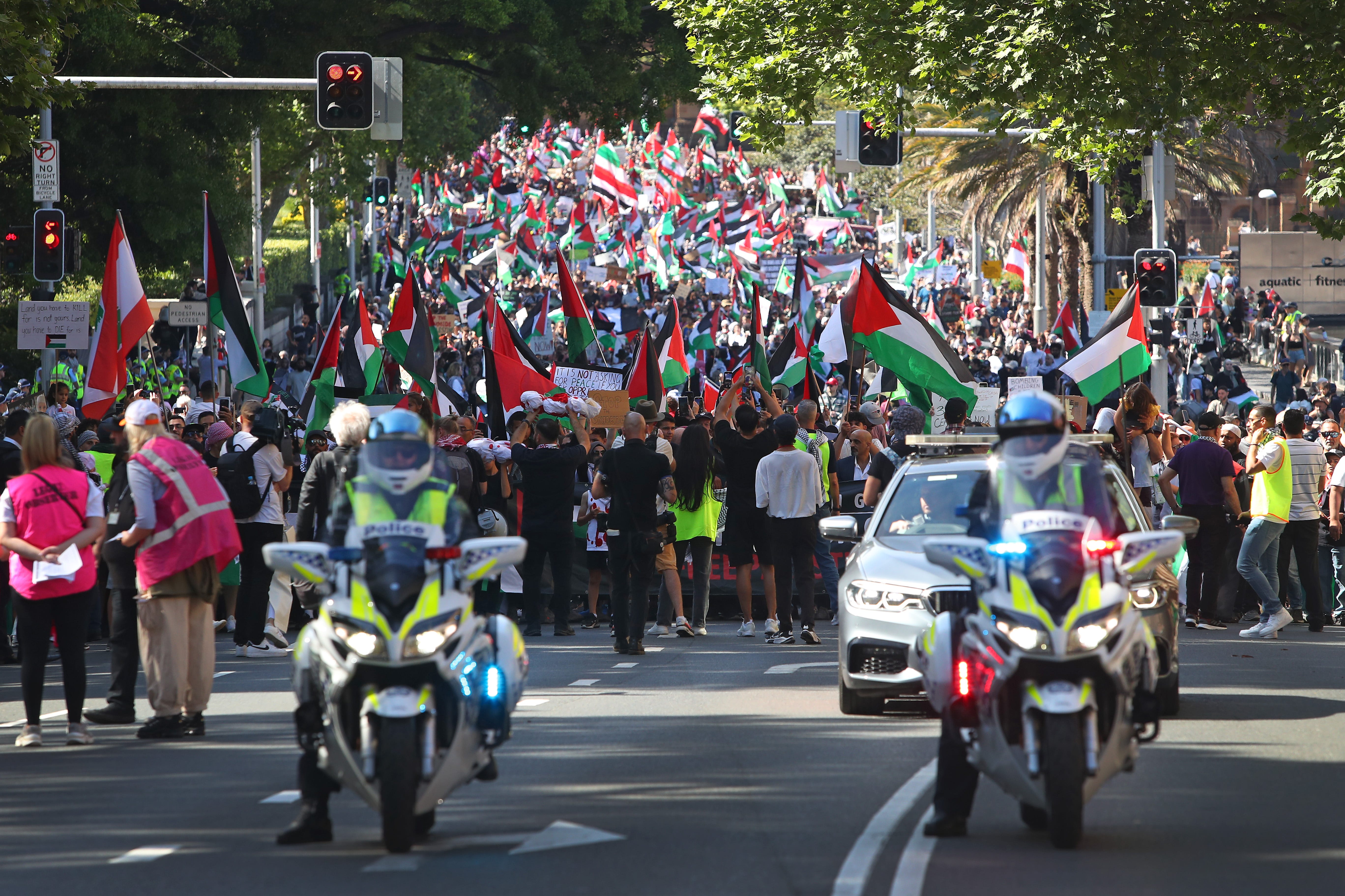 Demonstranten mit palästinensischen Flaggen marschieren auf einer Straße in Sydney, Australien.