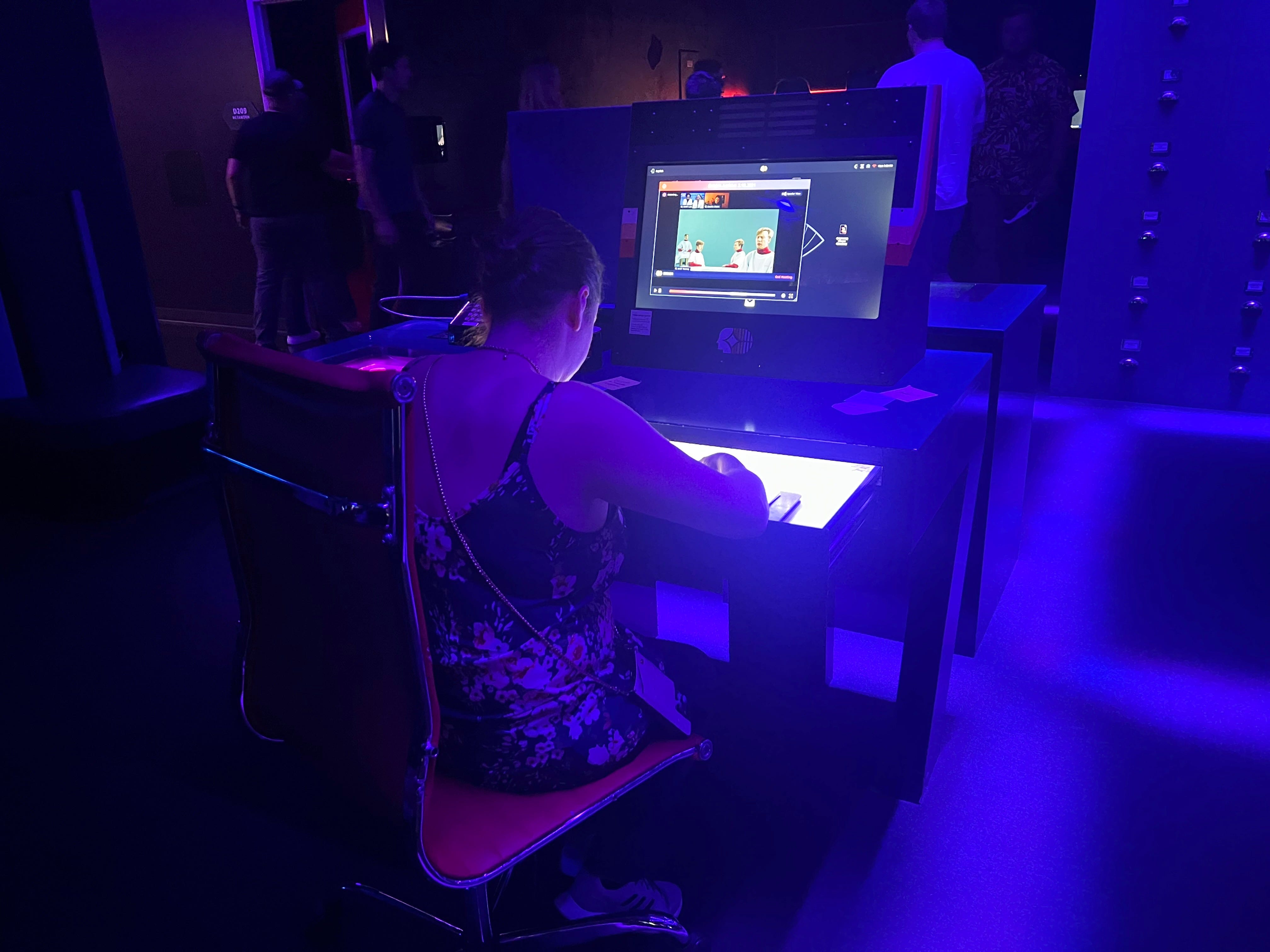 Eine Frau arbeitet am Computer im blau erleuchteten Büro.