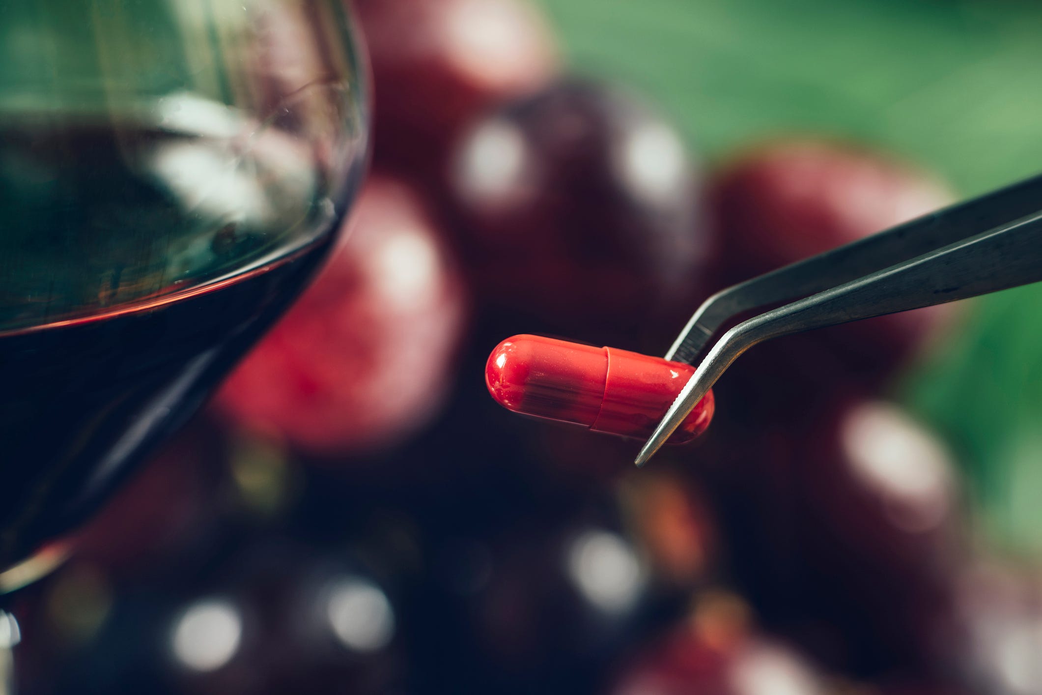 Eine rote Pille neben einem Weinglas