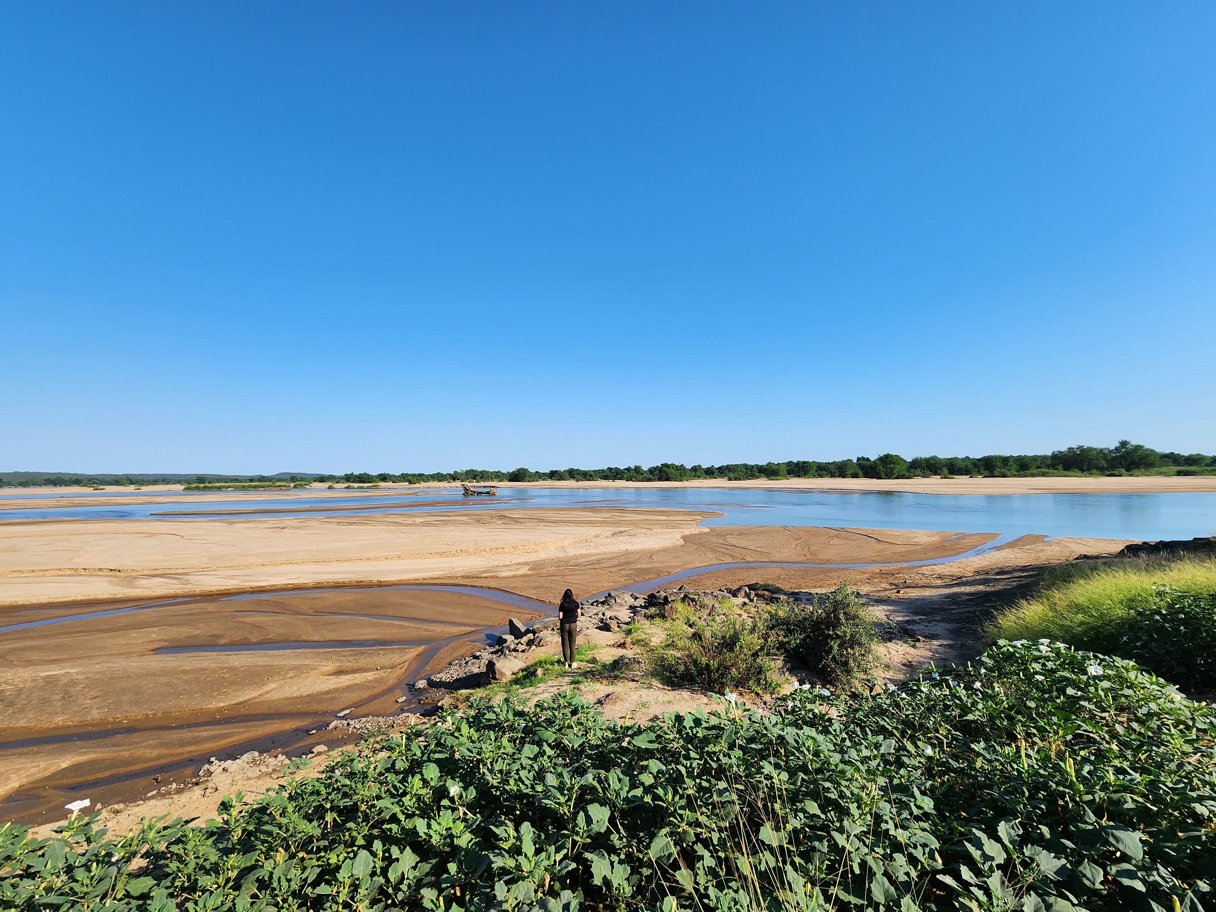 Wasser, Sand und Busch in Südafrika mit einer Frau, die weit weg in der Mitte steht