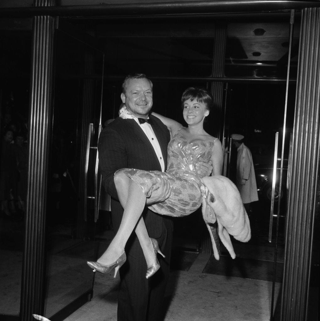 Der amerikanische Schauspieler Aldo Ray (1926 – 1991) trägt seine Frau Johanna bei der Londoner Premiere seines neuen Films „The Day They Robbed the Bank of England“, 18. Mai 1960.