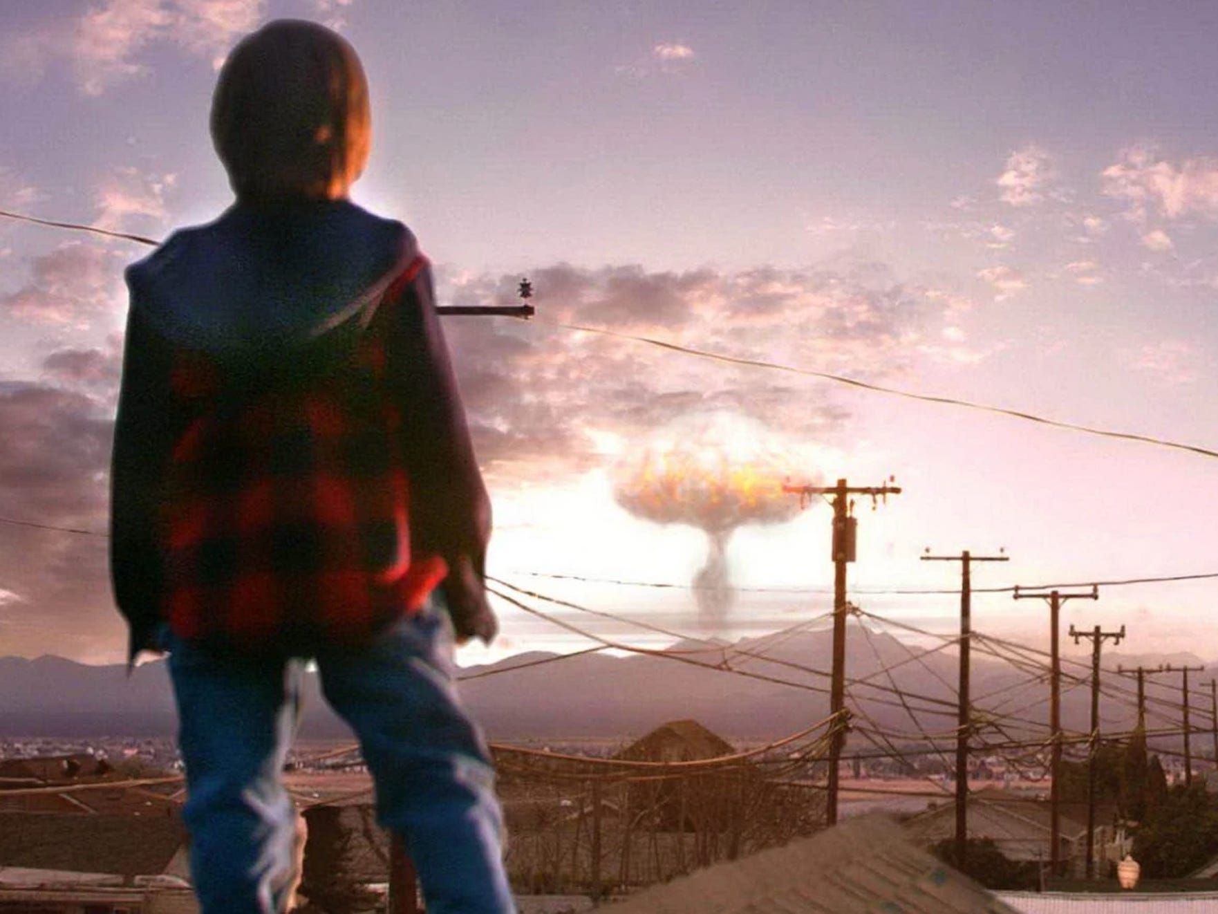 Ein kleiner Junge blickt auf eine Atomexplosion in der Ferne.