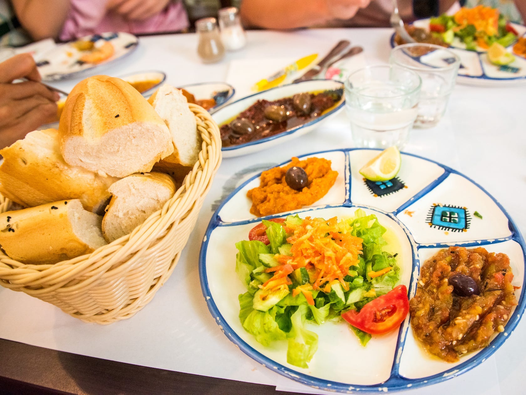 Nahaufnahme eines Tellers mit gemischten tunesischen Vorspeisen (Auberginen-Zaalouk, Salat, frittierte Brötchen, Oliven) in einem Restaurant in der Altstadt von Tunis, Tunesien, Nordafrika