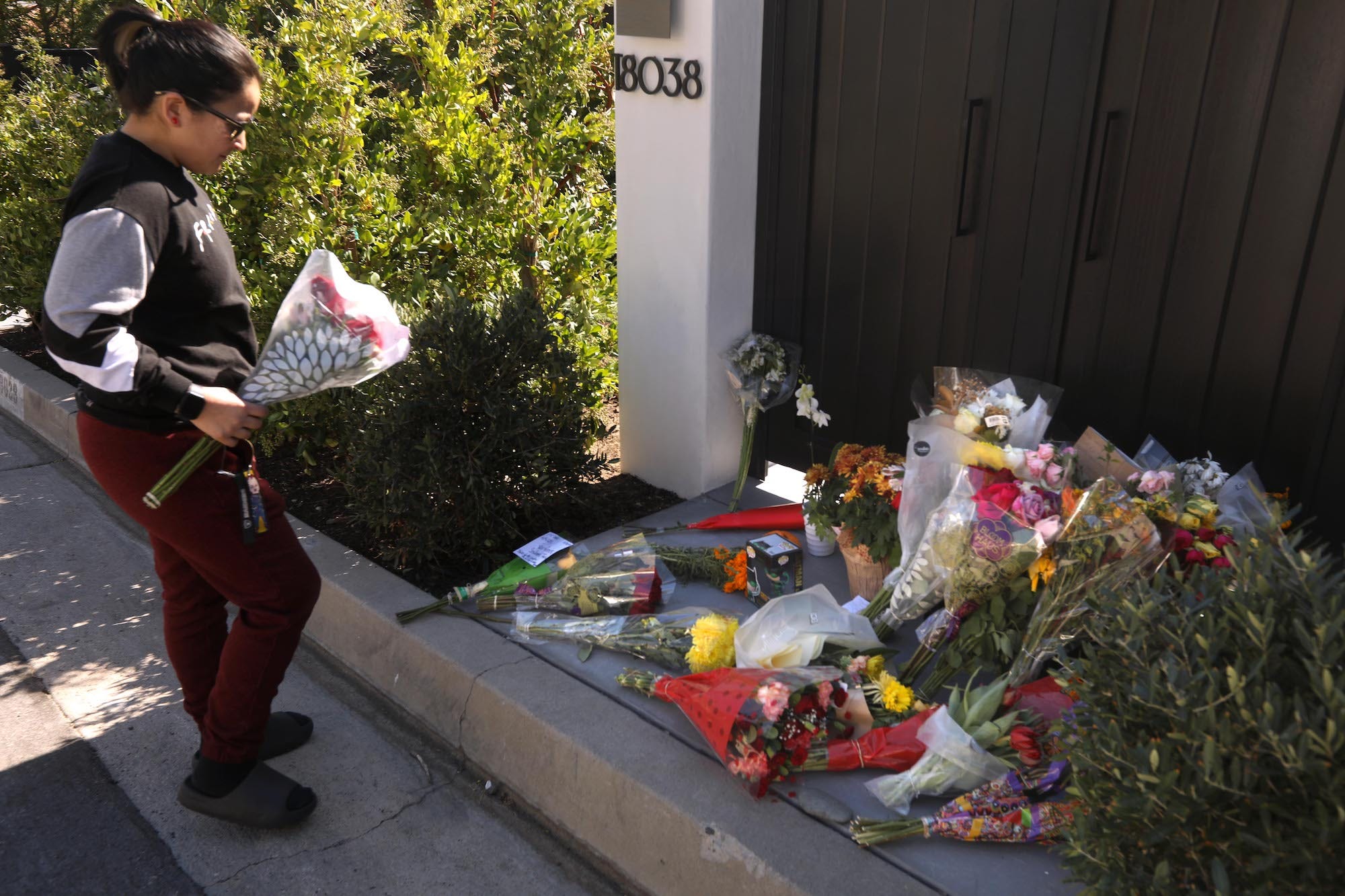 Daisy Muro aus Downey bereitet sich darauf vor, am 30. Oktober 2023 Blumen an einem wachsenden Denkmal für den Schauspieler Matthew Perry vor seinem Haus in Pacific Palisades niederzulegen.