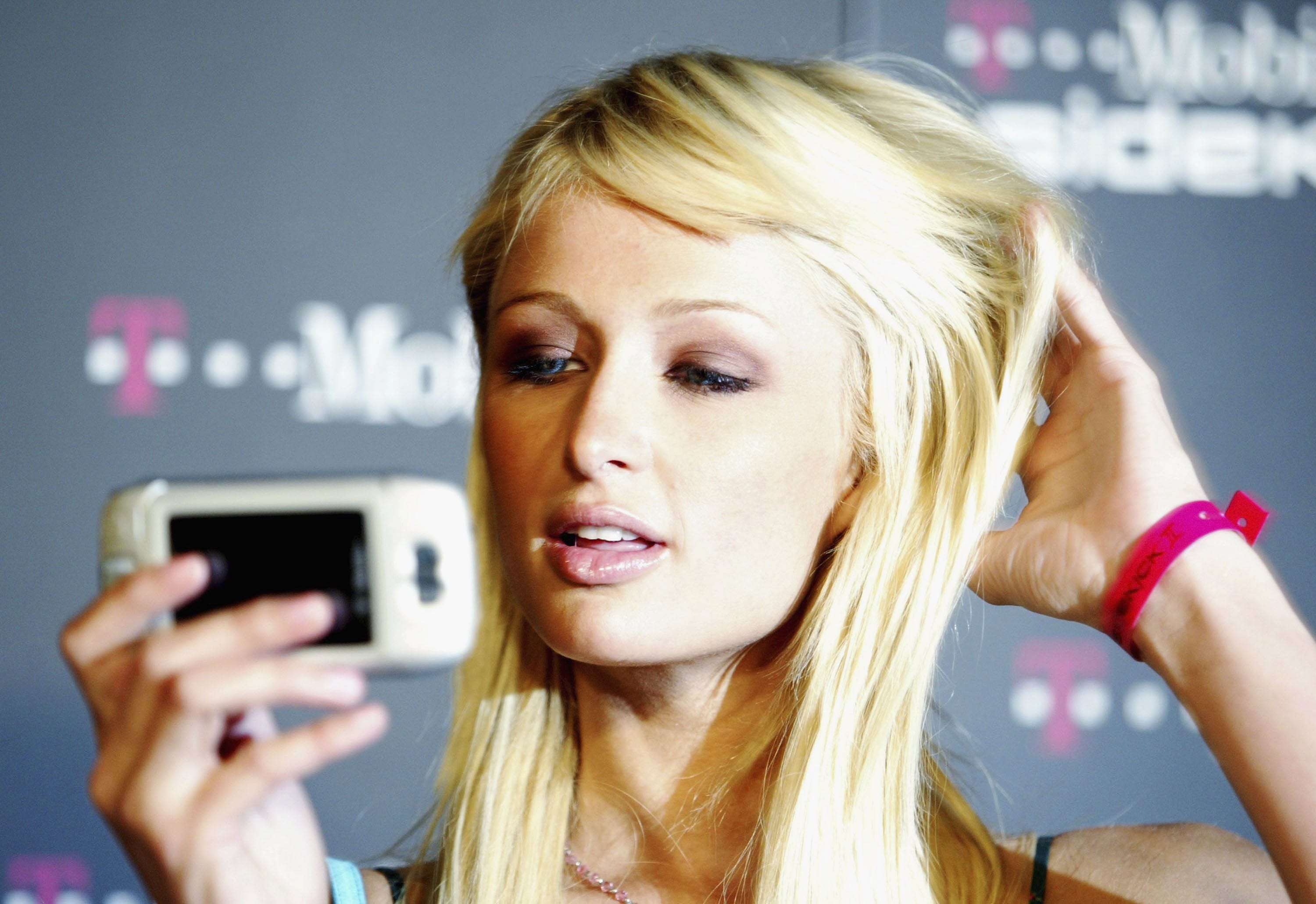 Paris Hilton hält ein Mobiltelefon.