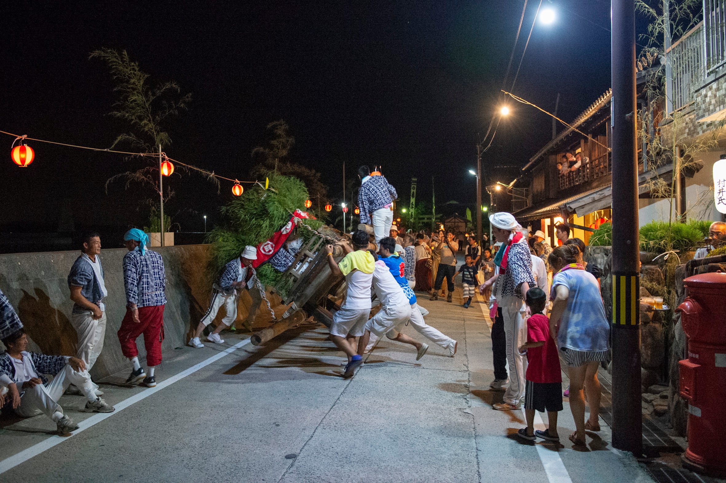 Männer auf der Straße in Japan bei Nacht, die eine Holzkonstruktion für ein Festival tragen