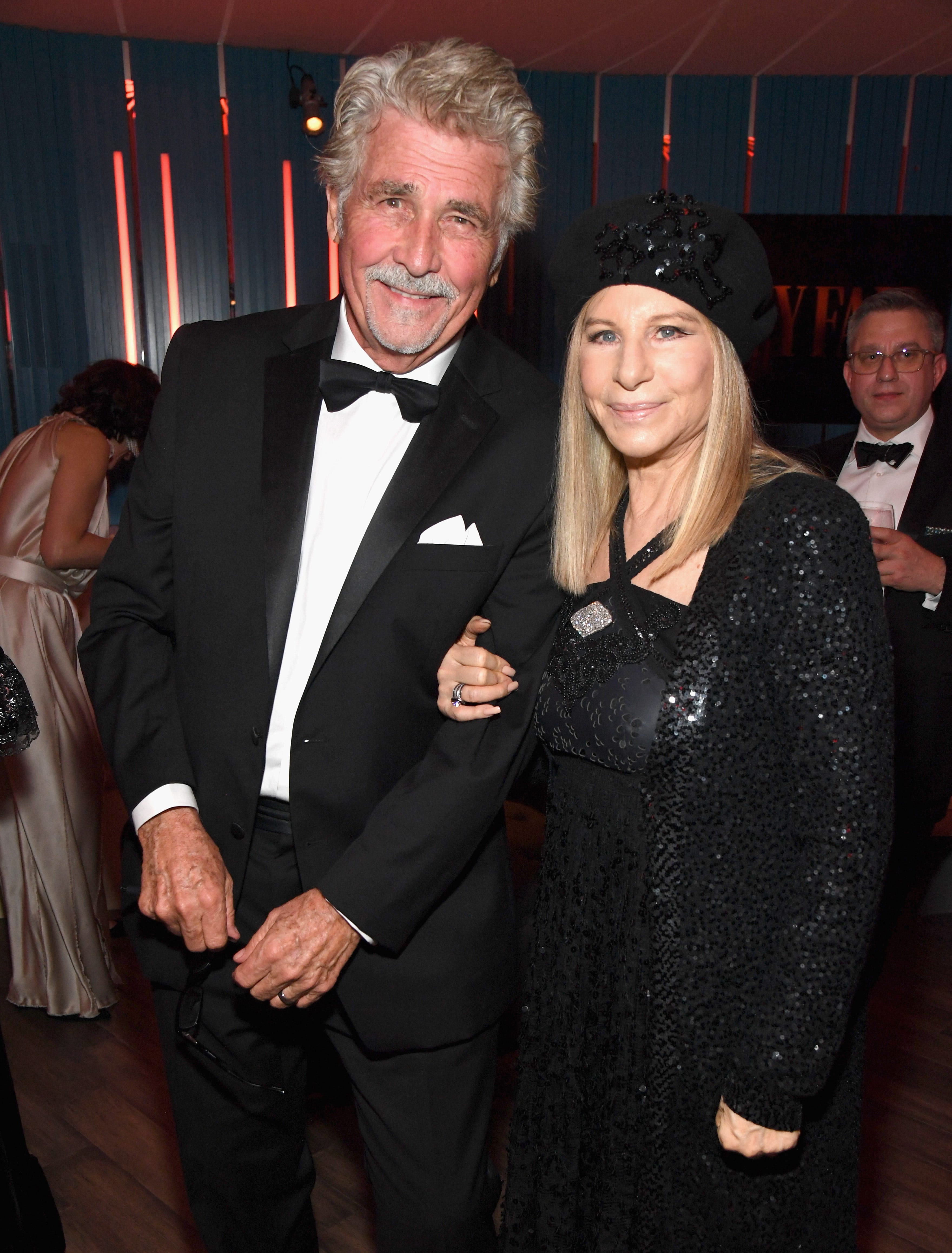 James Brolin posiert im Smoking mit Barbra Streisand in einem schwarzen Perlenkleid und passender Jacke und Hut auf einer Party.