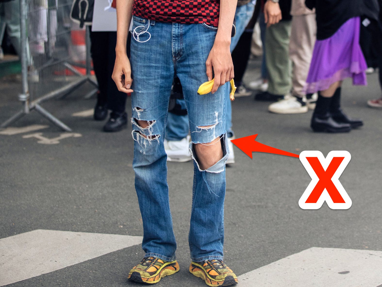 Ein x zeigt auf zerrissene Jeans.
