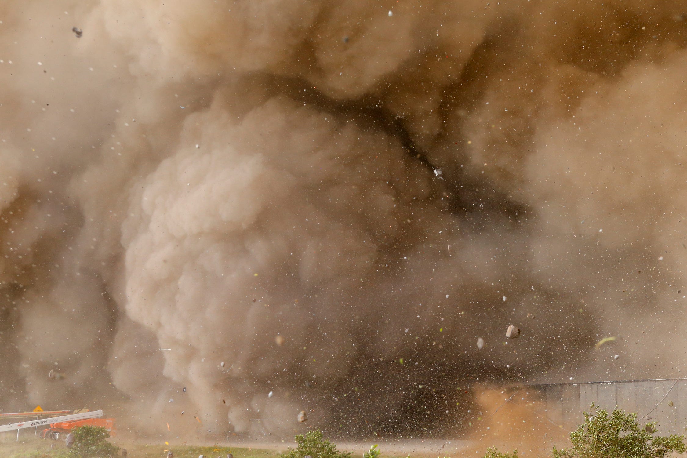 Riesige Rauchwolke mit herumfliegenden Steinen und Trümmern vom Raketenstart eines Raumschiffs verschluckt die Ausrüstung, die ein Grundstück mit Büschen umzäunt