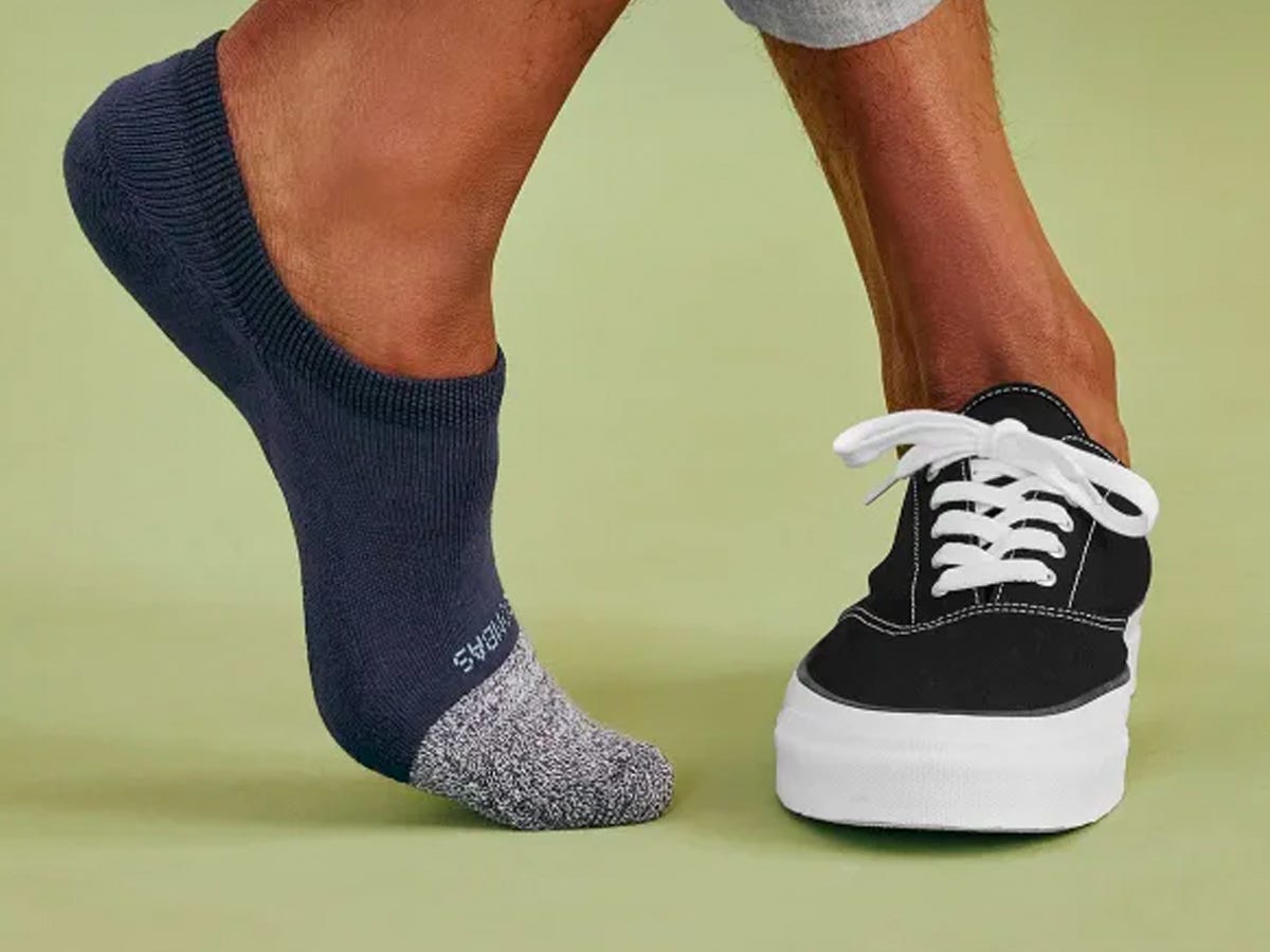 Dargestellt sind die Füße einer Person mit einem Schuh an einem Fuß und einer nicht sichtbaren Socke am anderen.