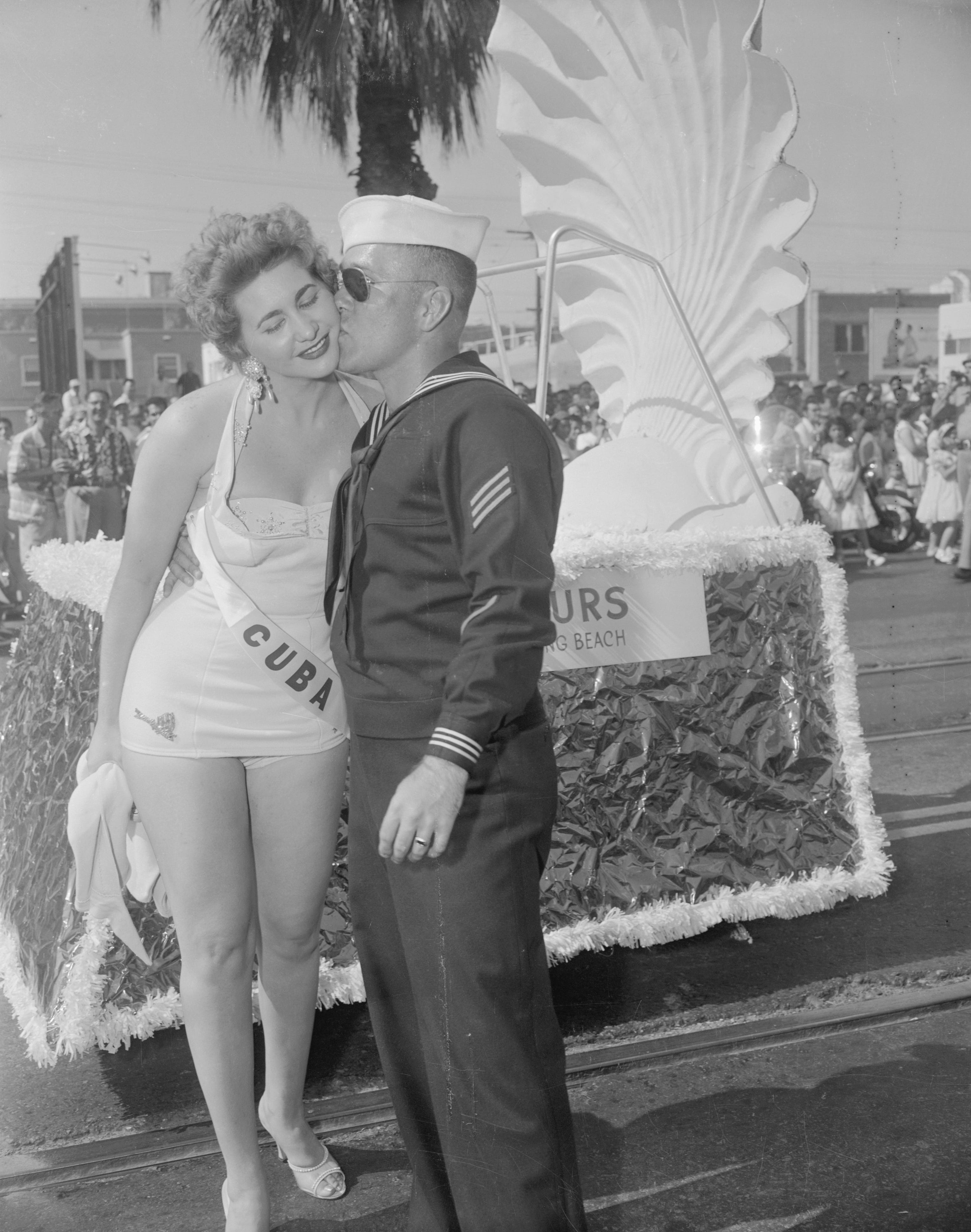 Long Beach, Kalifornien: Ein Schönheitsfresser ist dieser Segler, der sich heute freiwillig als mobile Truppe für den Festwagen der „Miss Cuba“ bei der „Miss Universe“-Parade gemeldet hat.  Am Ende der zwei Meilen heißen Fahrt wurde der junge Segler mit einem Kuss belohnt.
