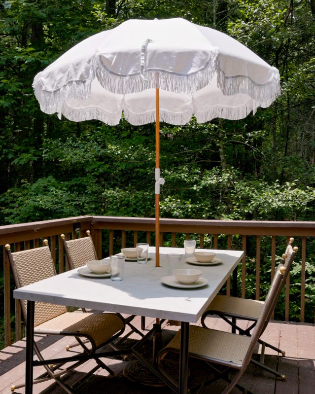 Sitzschirm im Freien mit weißen Fransen über einem Marmortisch auf einer Terrasse