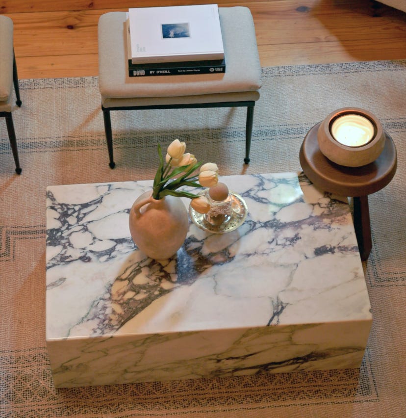 Marmorblocktisch auf beigem Teppich mit Blumentopf darauf