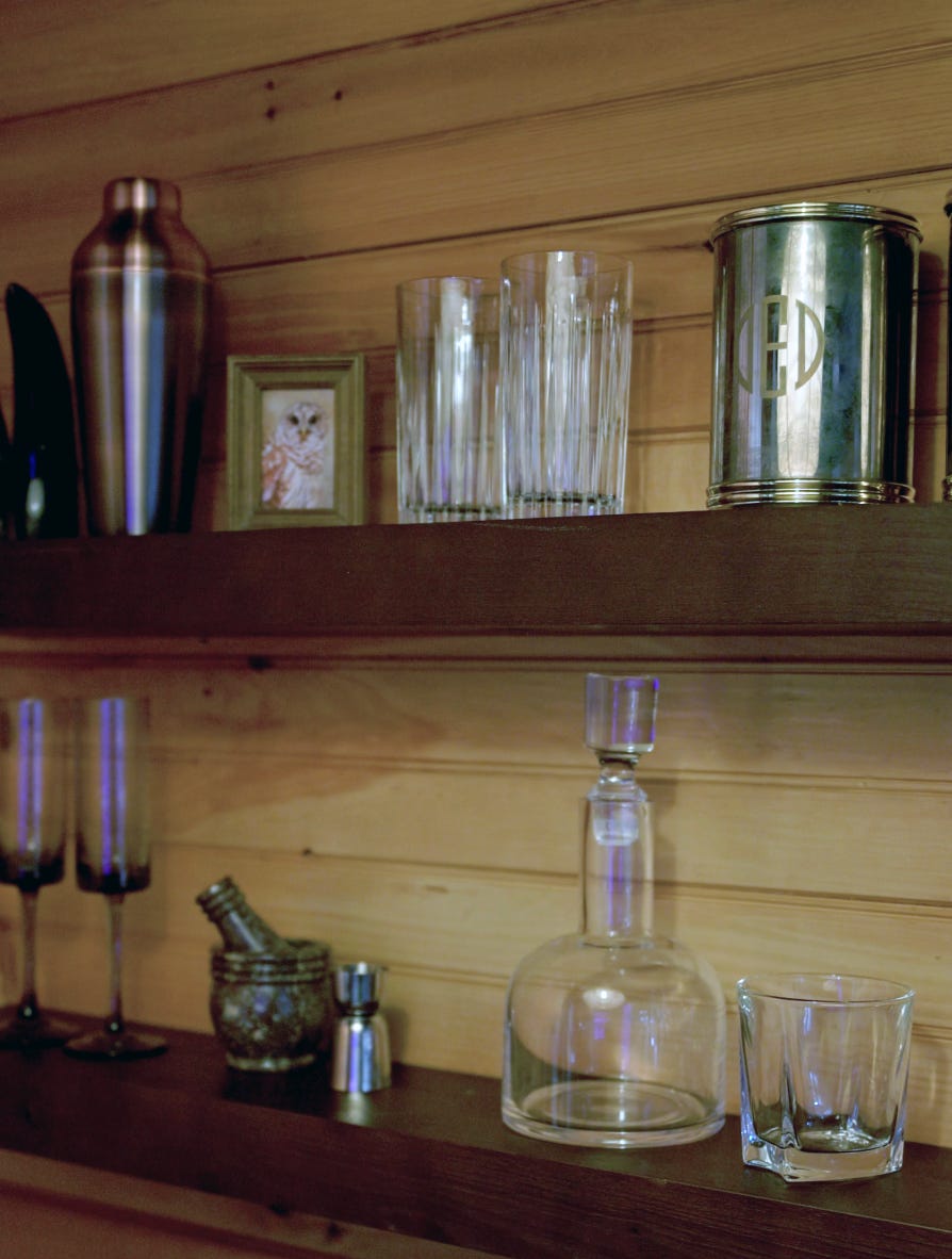 Holzregale mit Glasbechern und -behältern neben einem Eiskübel aus Metall