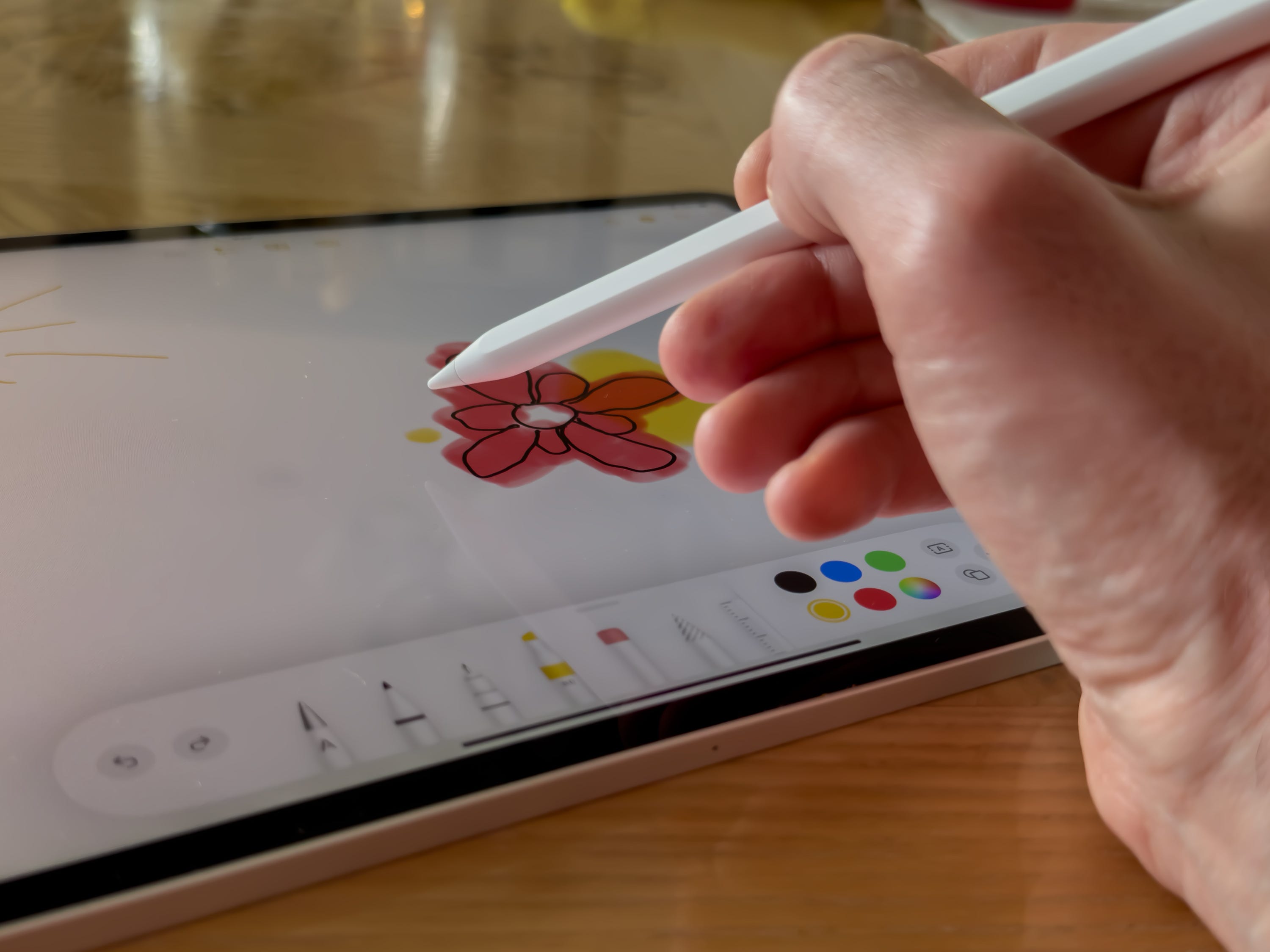 Apple 2022 iPad Pro mit dem Apple Pencil der zweiten Generation, gehalten von einer Hand, die eine Blume zeichnet.