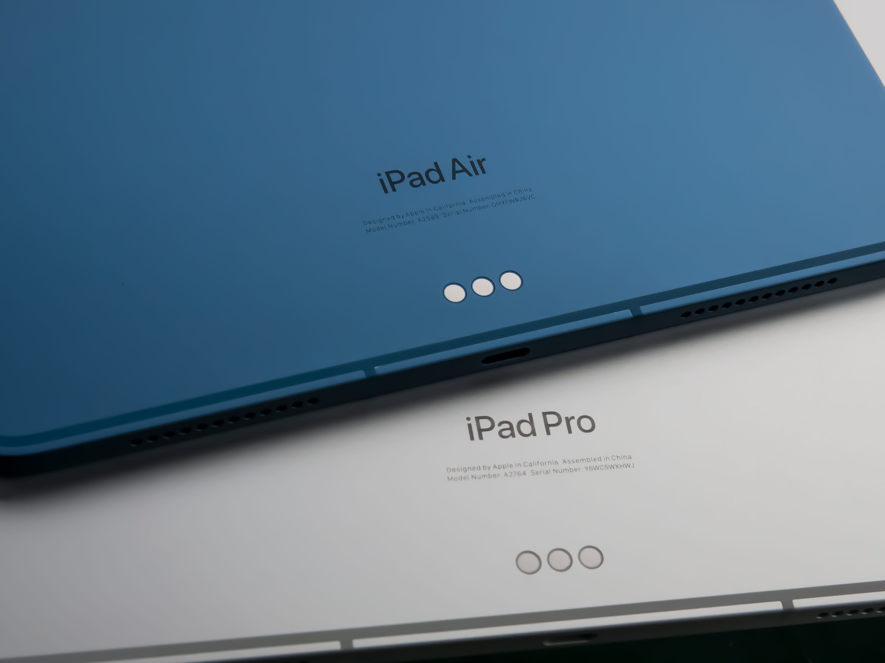 Die unteren Rückseiten des 2022 iPad Air und des 2022 iPad Pro übereinander gestapelt mit ihren Modellnamen.