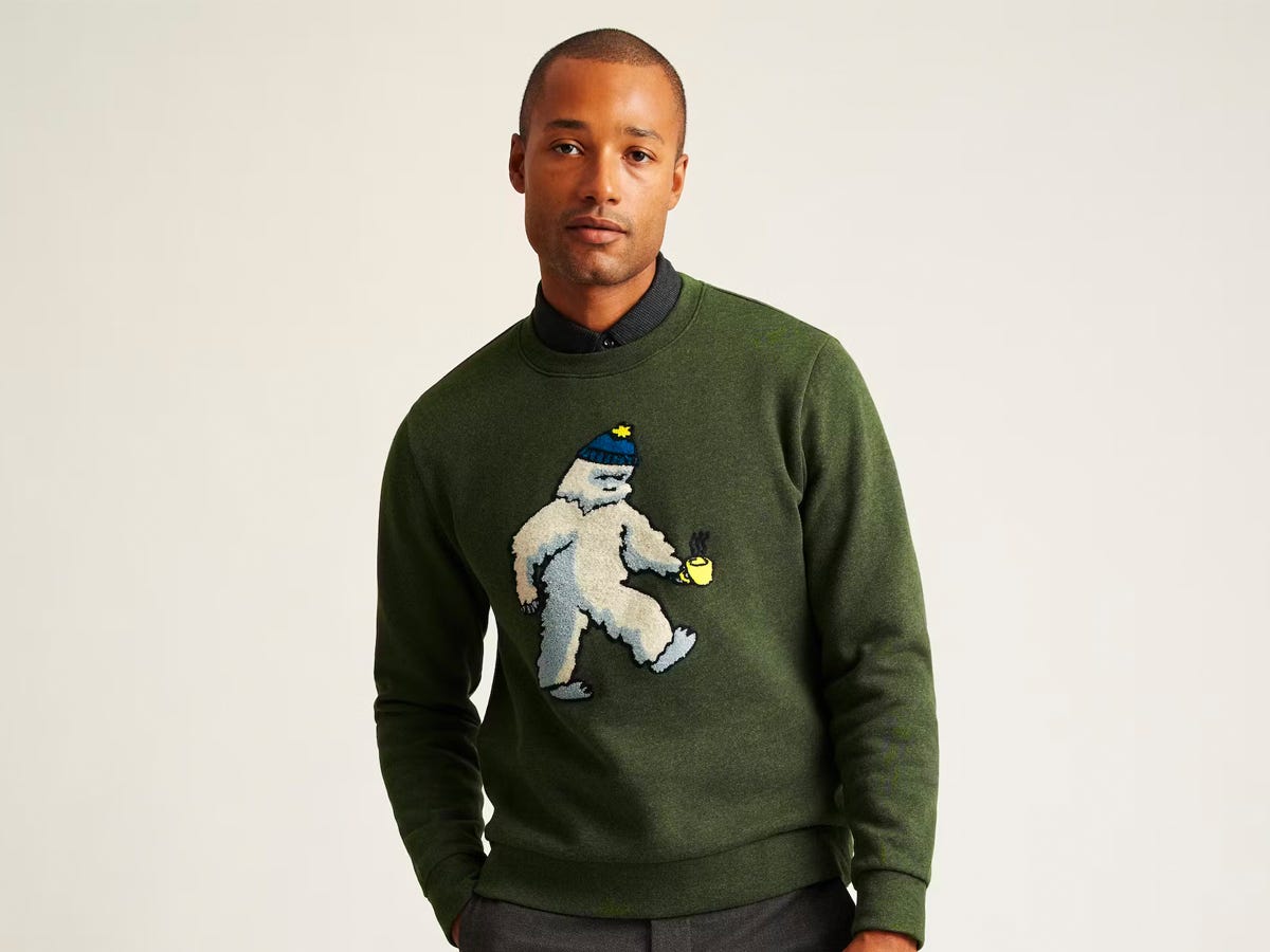 Person, die einen grünen Pullover mit Rundhalsausschnitt und Yeti-Motiv trägt.