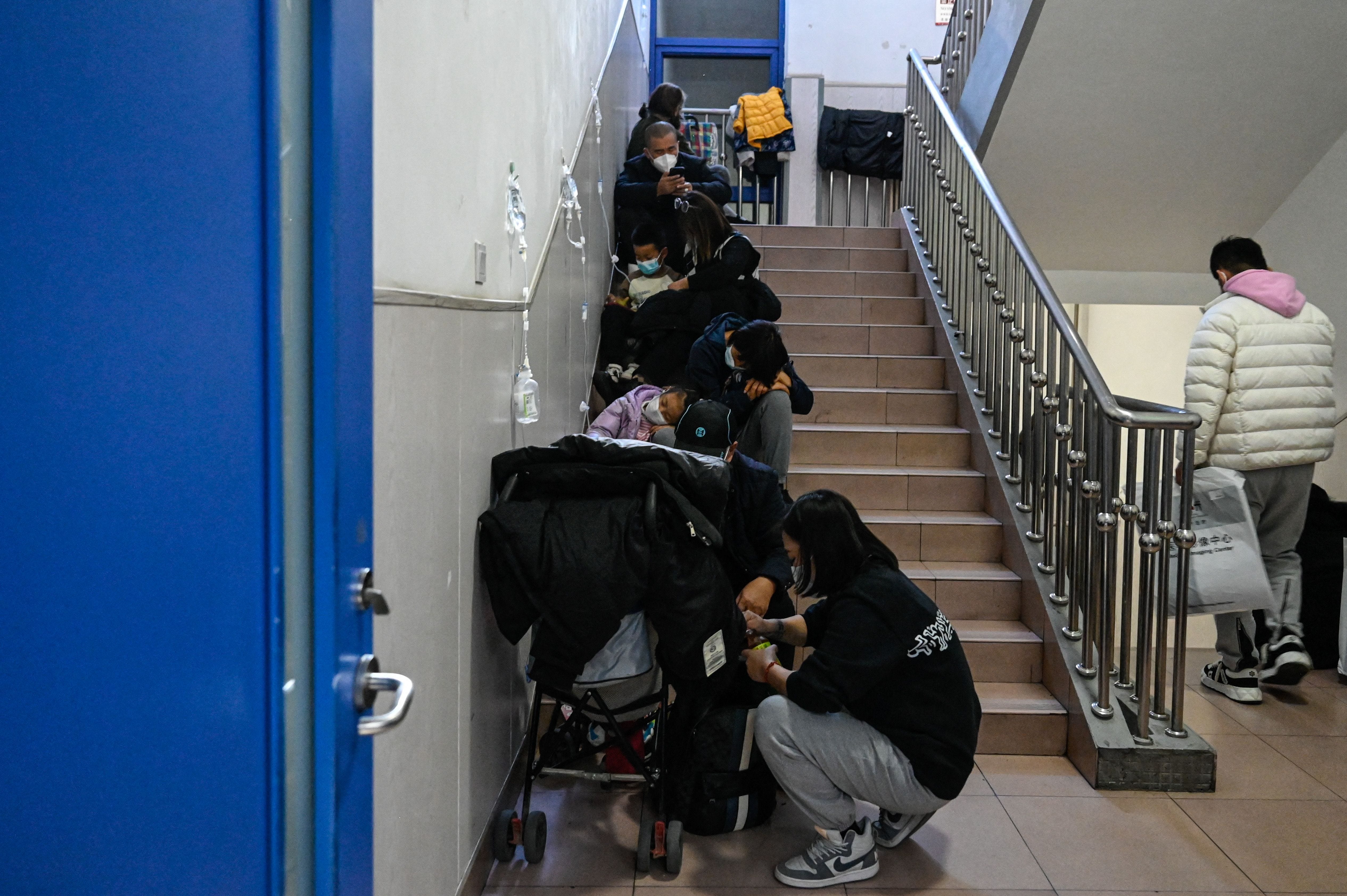 Am 23. November 2023 warten Kinder auf der Treppe eines Kinderkrankenhauses in Peking, einige werden mit Infusionen verabreicht.