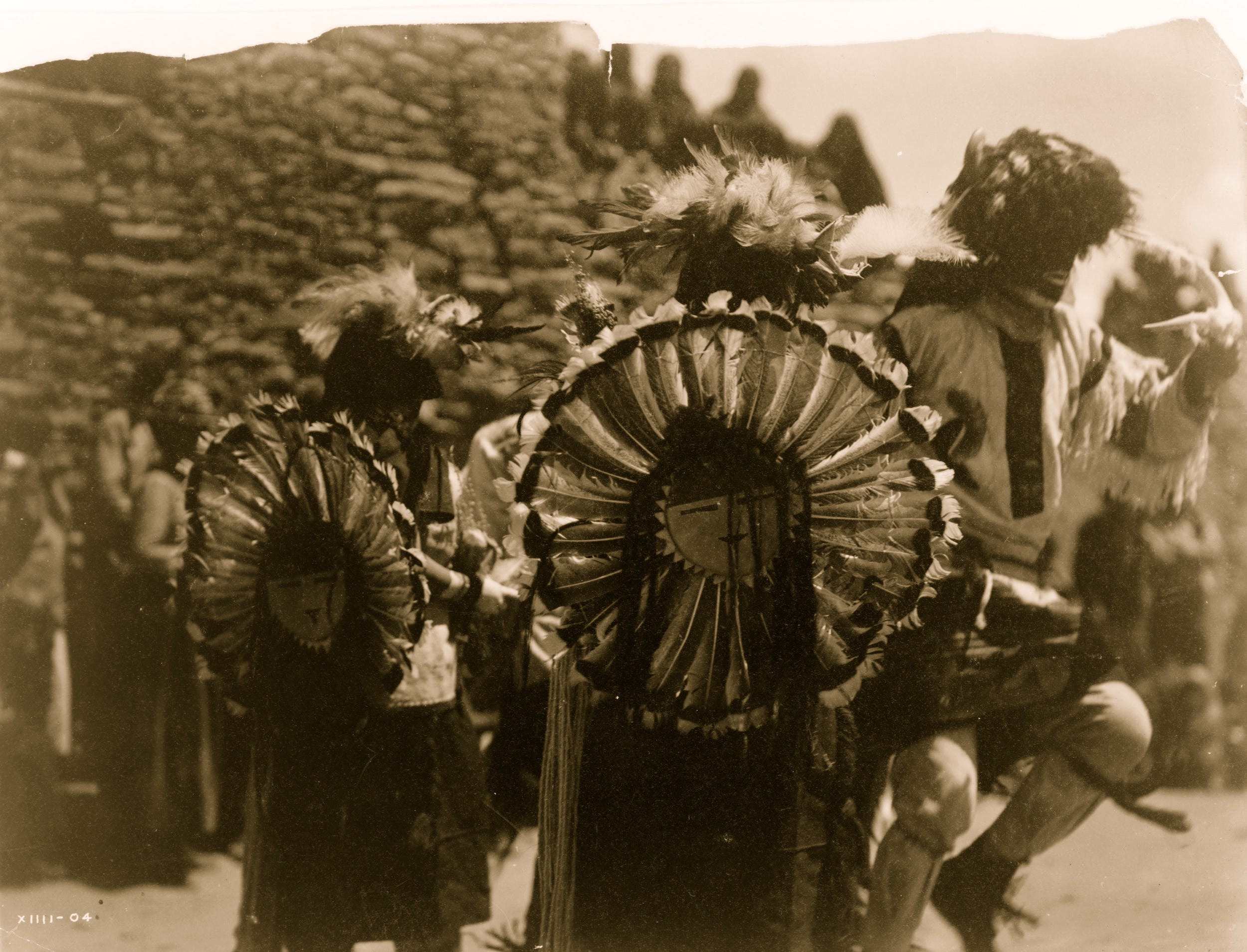 Kostümierte Tänzer tragen Tanzbüscheln des Sonnengottes Tewa aus Truthahnfedern