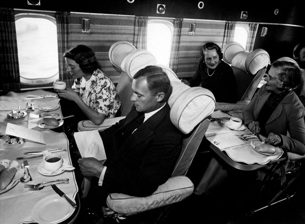 Passagiere essen in einem Flugzeug in den 1950er Jahren eine Mahlzeit.